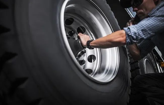 A man is changing a tire on a machine in a garage.