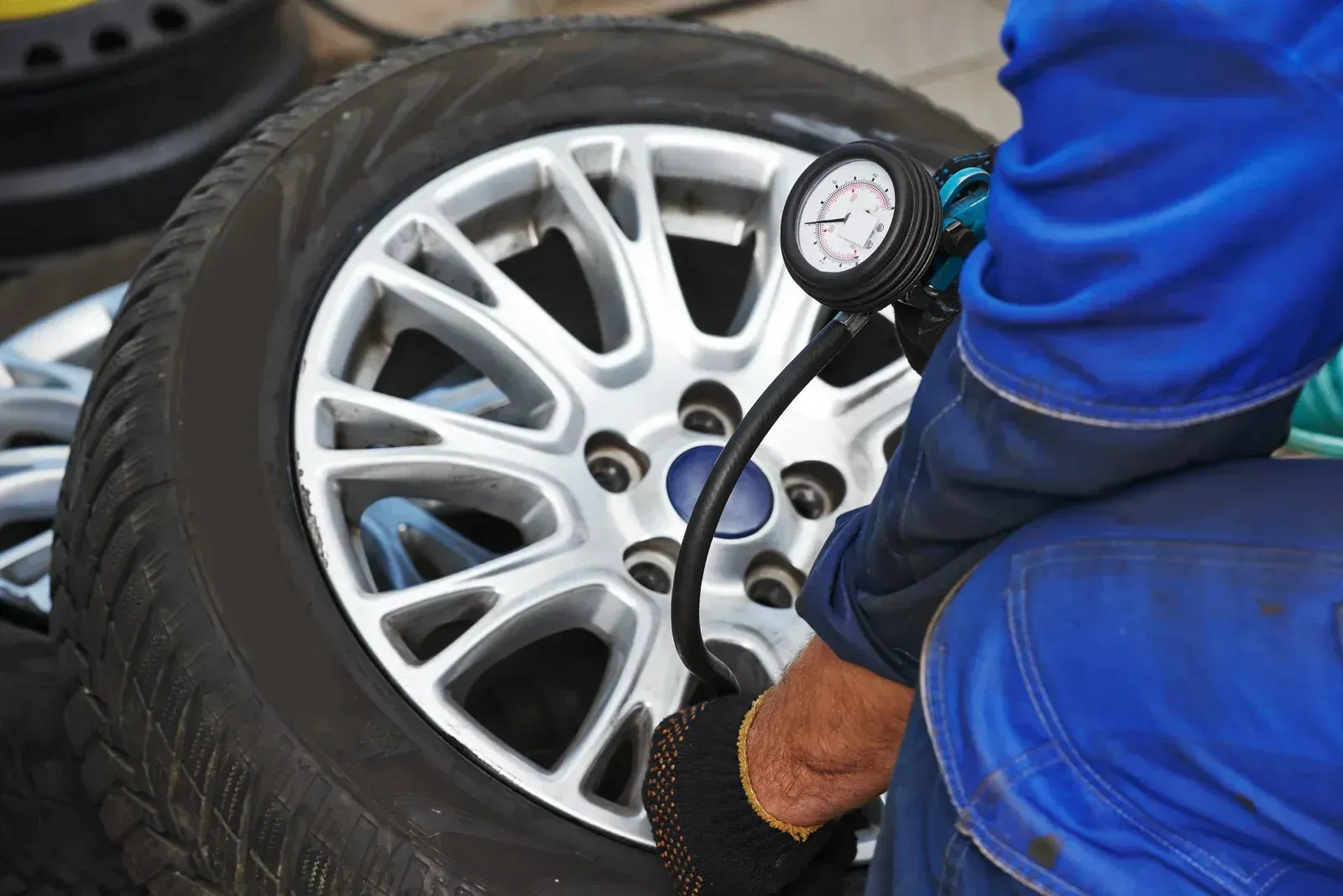 A man is pumping air into a tire with a gauge.