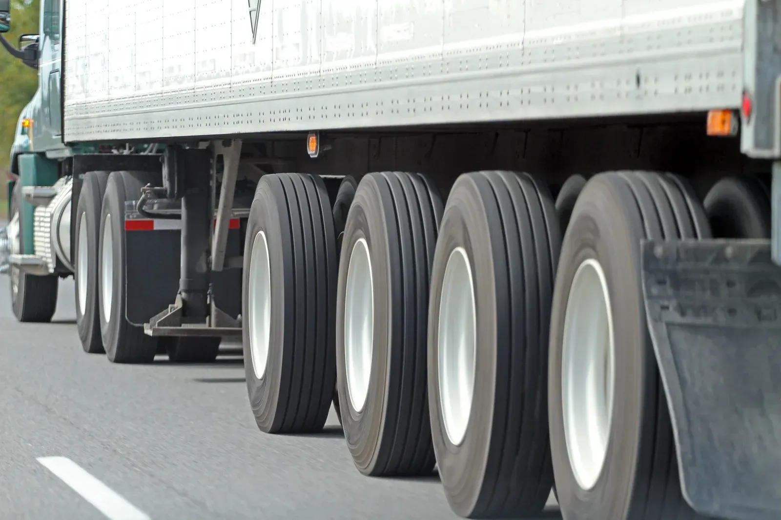 A semi truck is driving down a highway with many tires