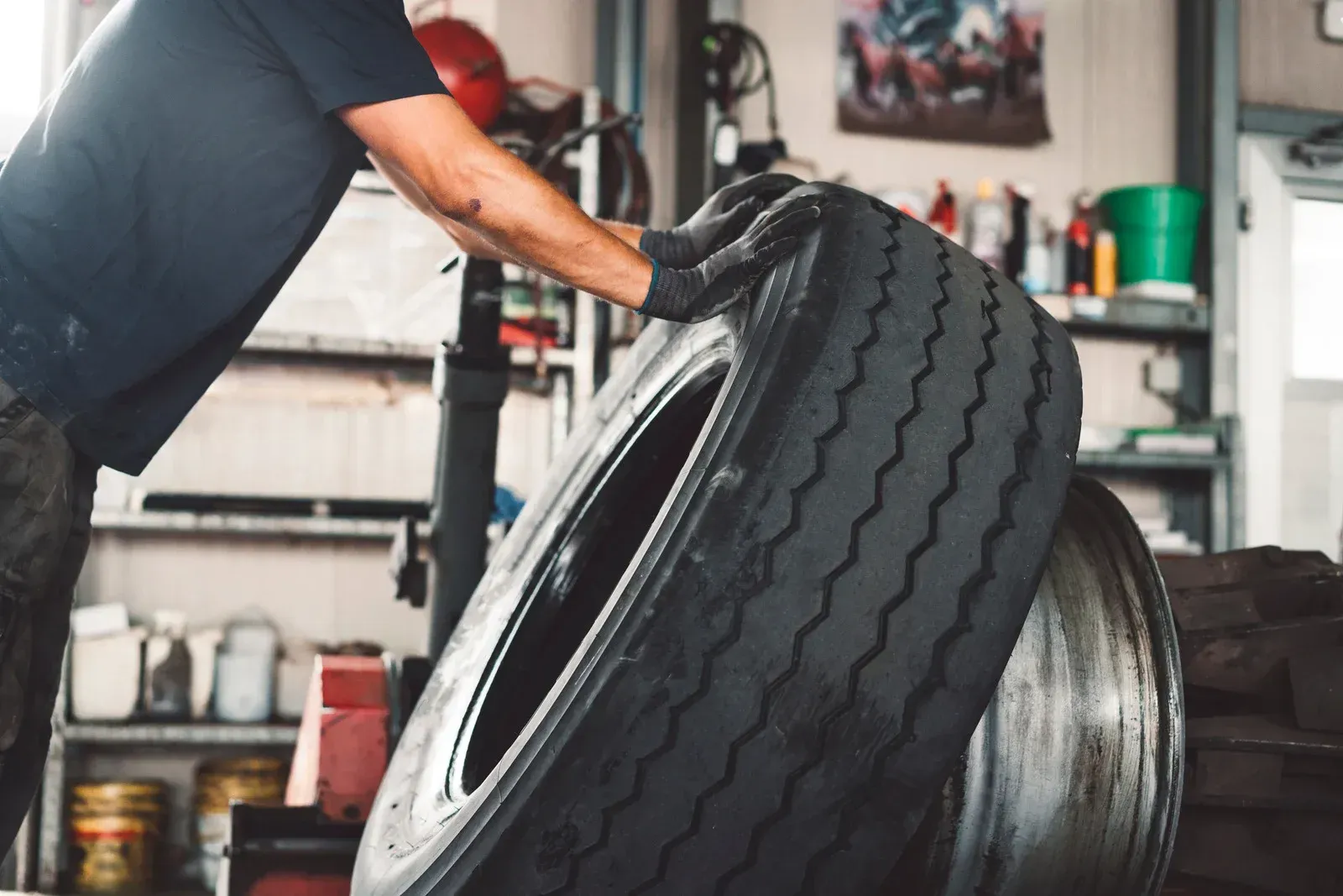 A man is changing a tire on a machine in a garage.