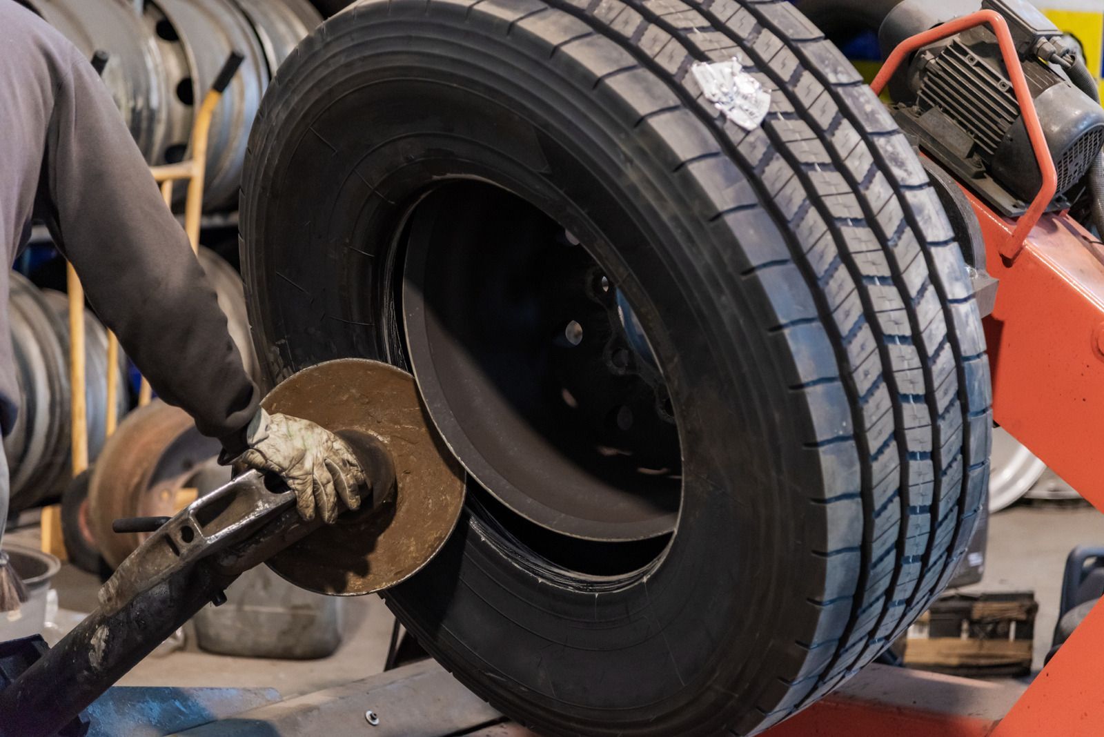 A man is balancing a tire on a machine in a garage.