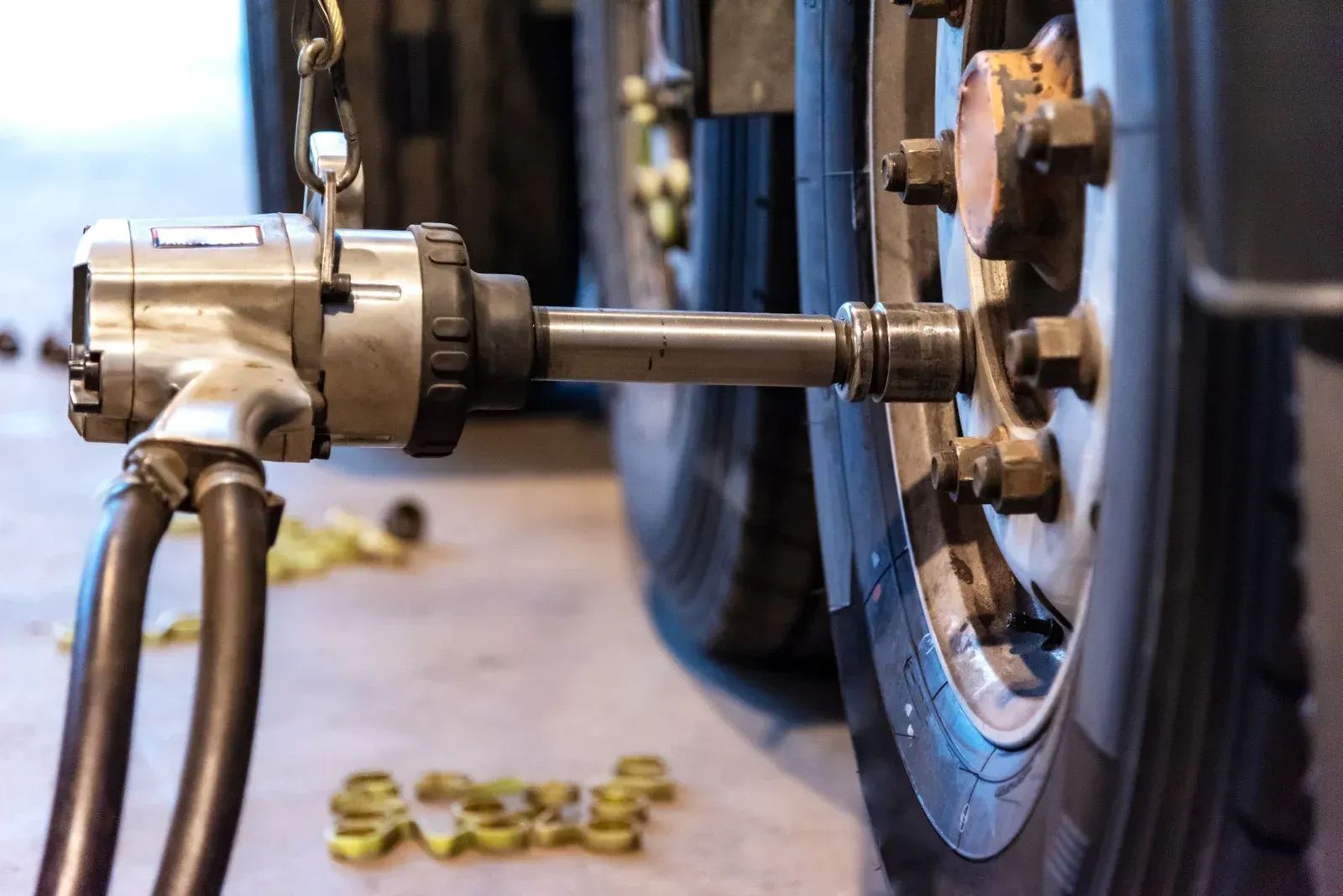 An air tool removing lug nuts from a truck wheel in a garage setting.