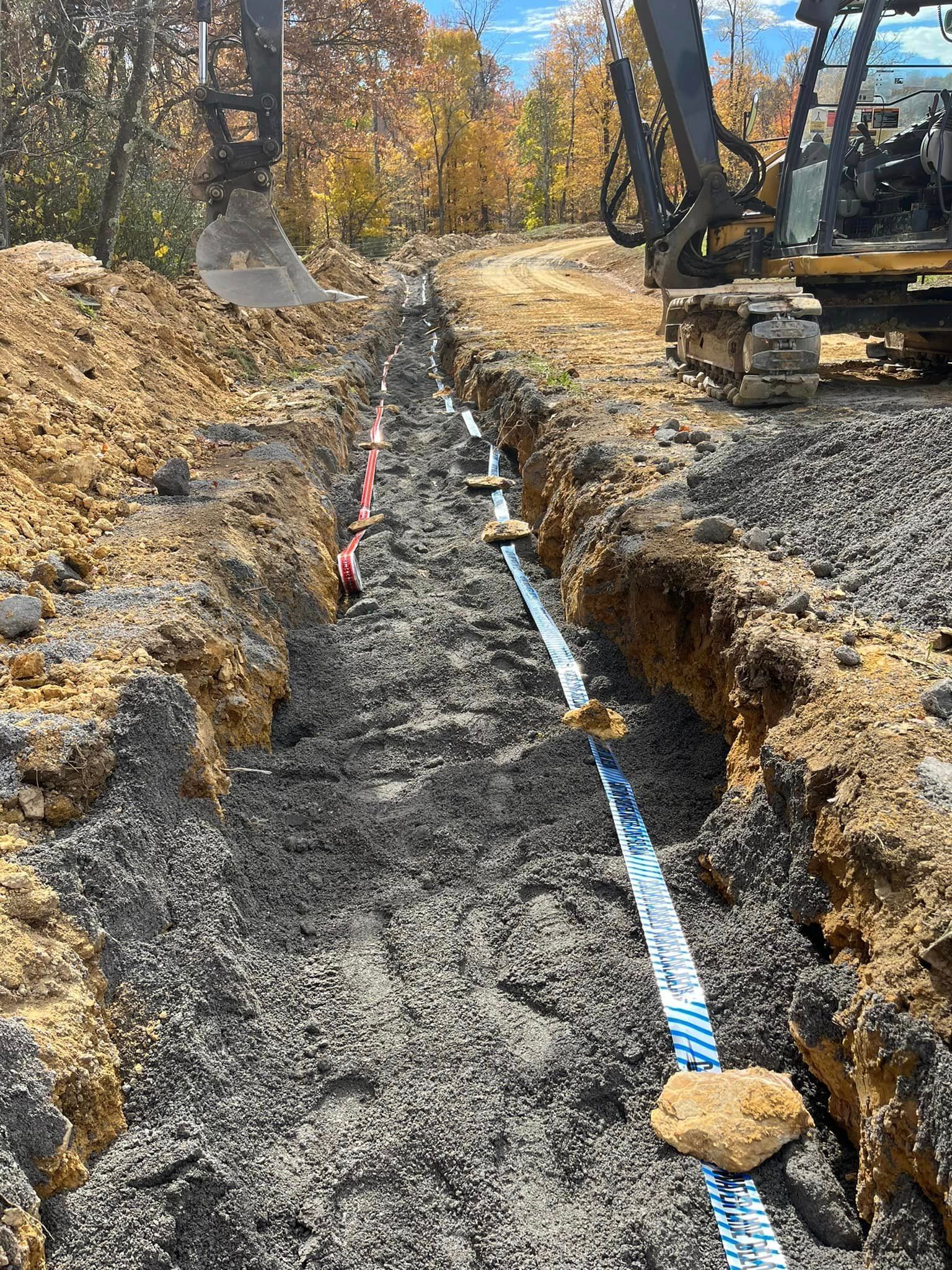A bulldozer is digging a trench in the dirt next to a road.