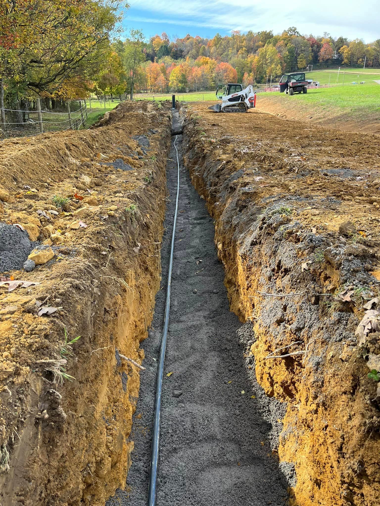 A trench is being dug in the dirt in a field.