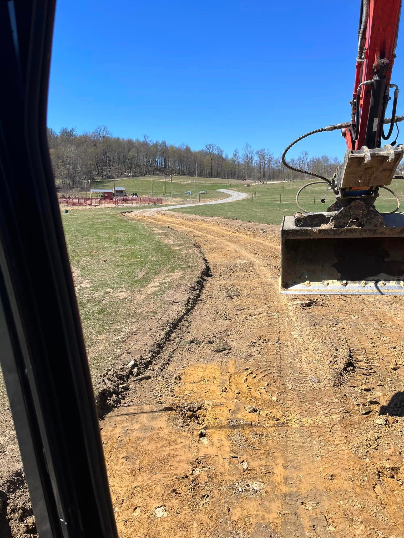 A bulldozer is moving dirt on a dirt road in a field.