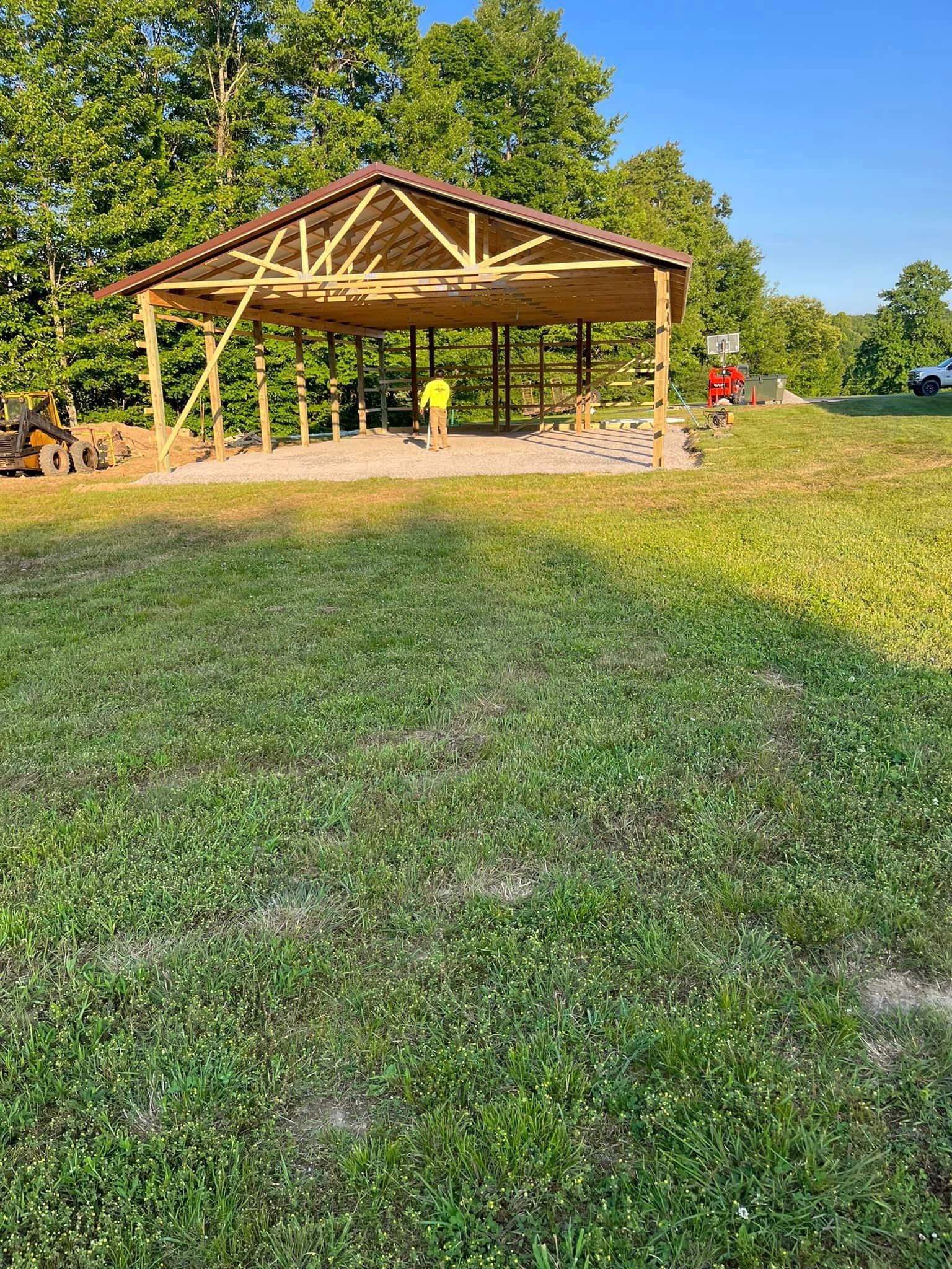 A wooden pavilion is being built in the middle of a grassy field.