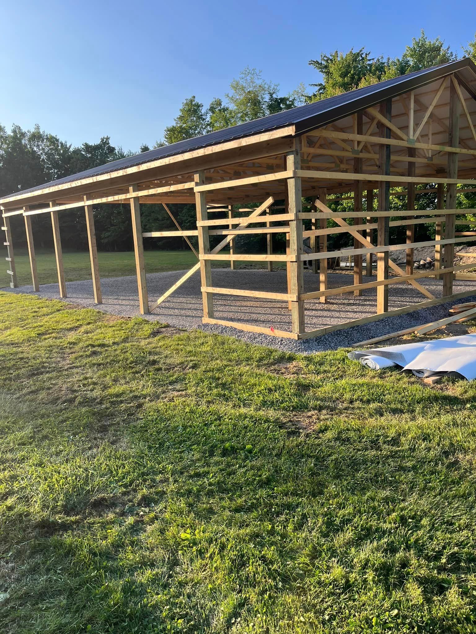 A wooden building is being built in the middle of a grassy field.