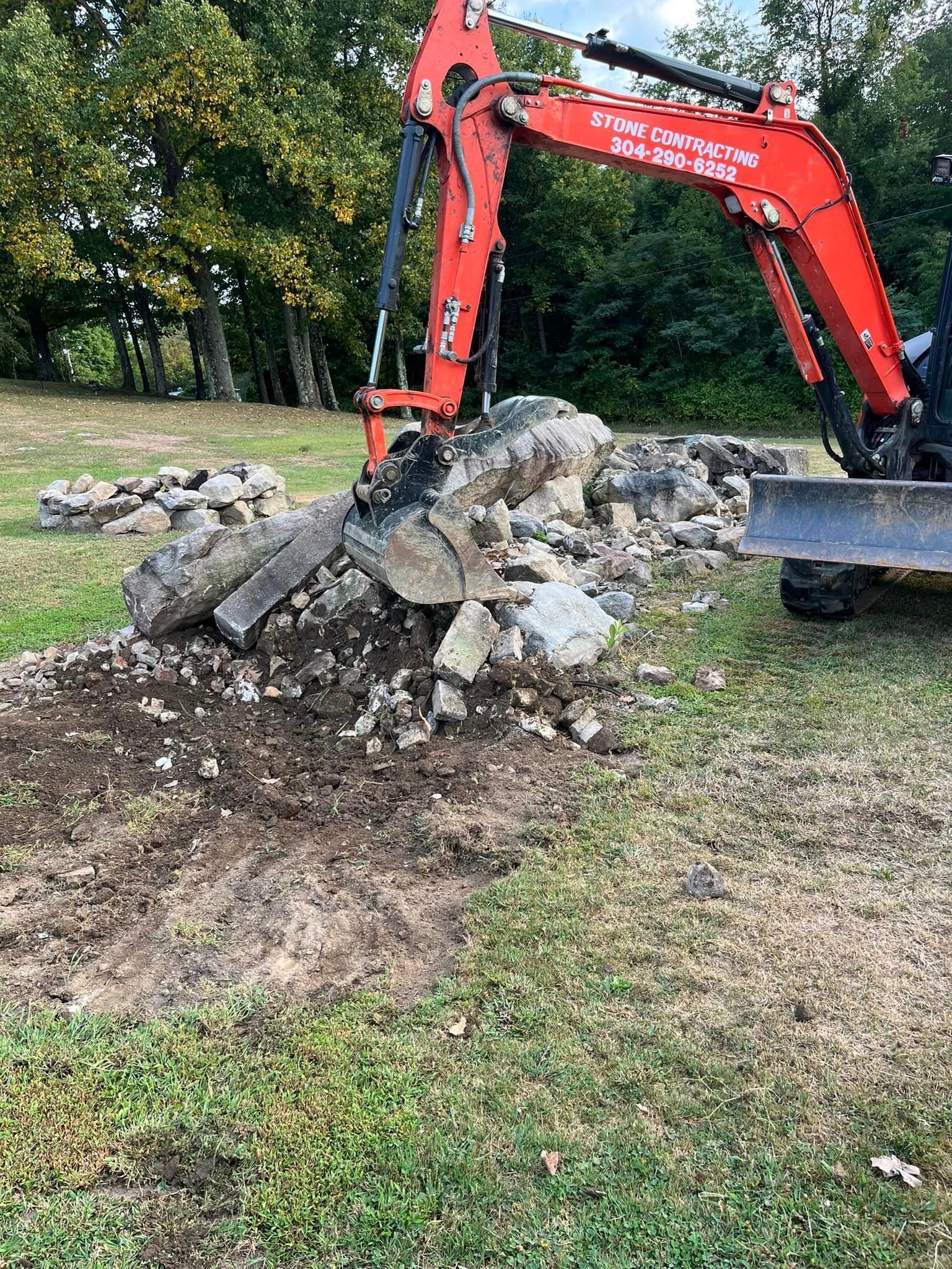 A red excavator is digging a hole in the grass.