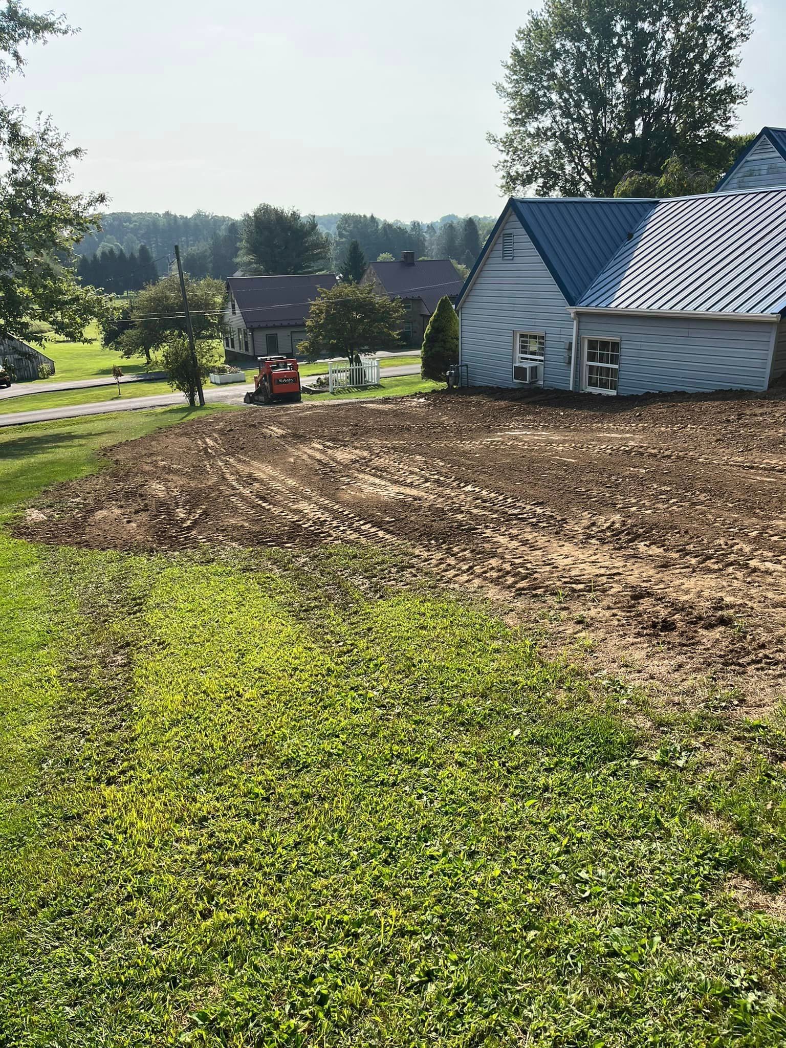 A white house with a blue roof is sitting on top of a lush green field.
