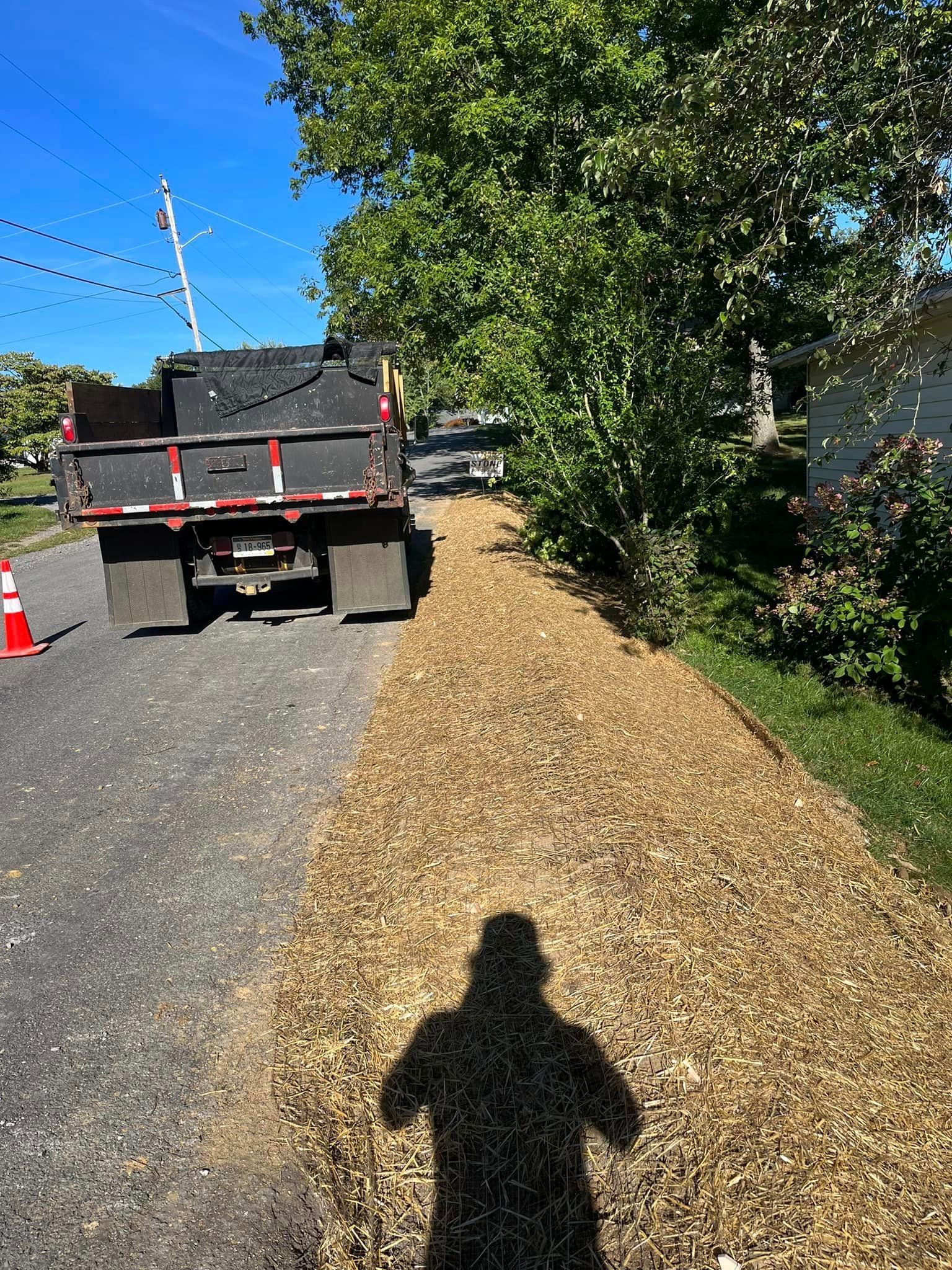 A dump truck is driving down a road next to a sidewalk.