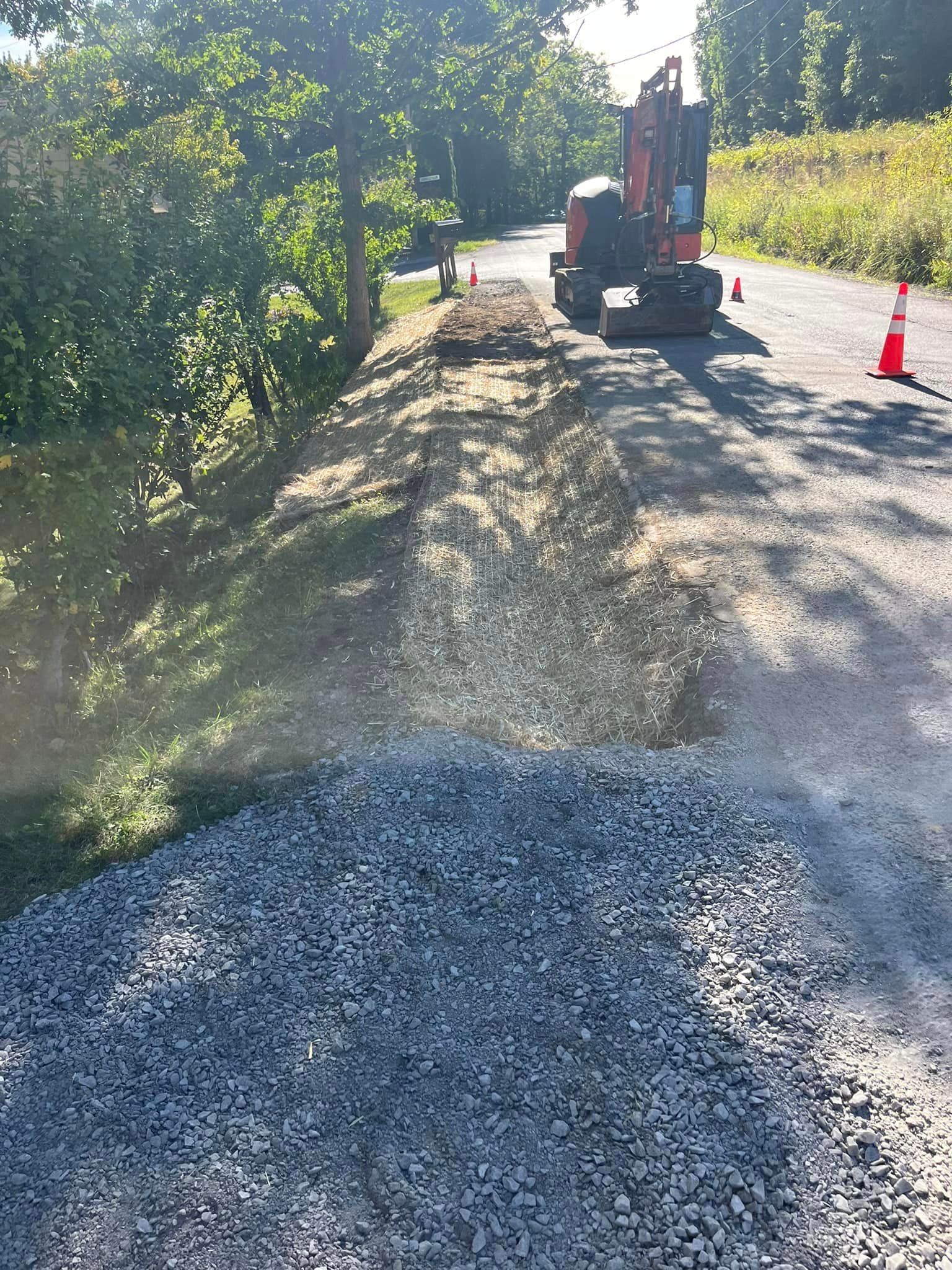 A bulldozer is driving down a gravel road next to a pile of gravel.