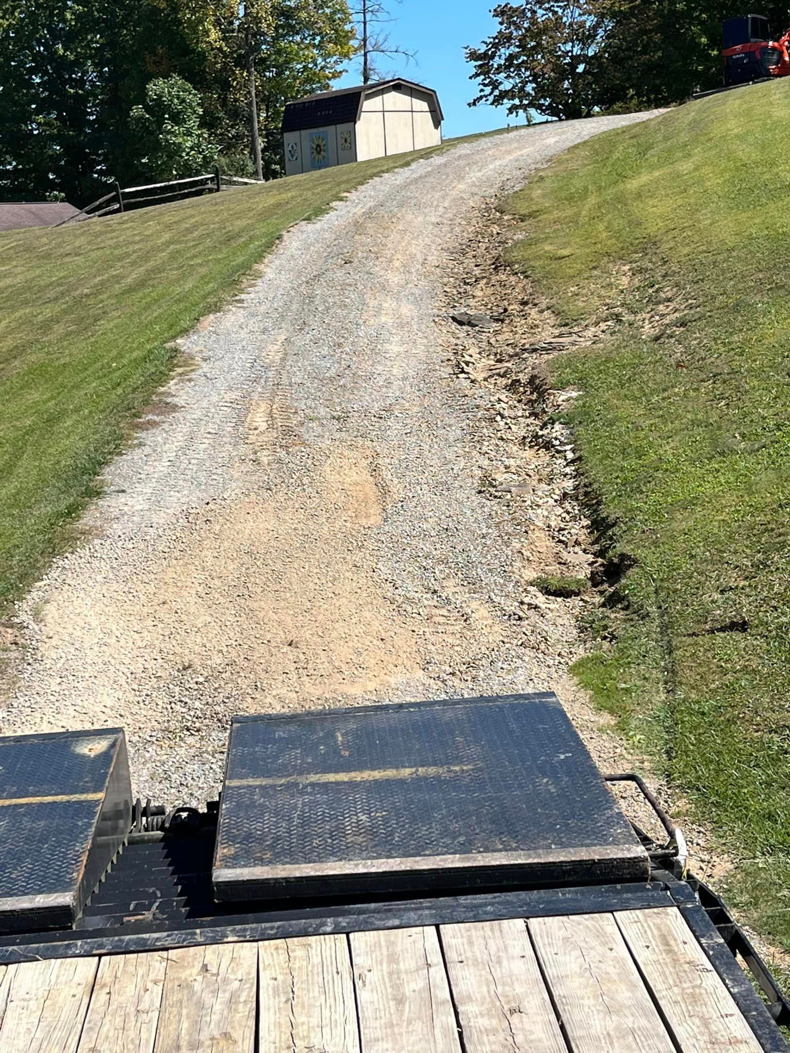 A dirt road going up a hill with a house in the background.