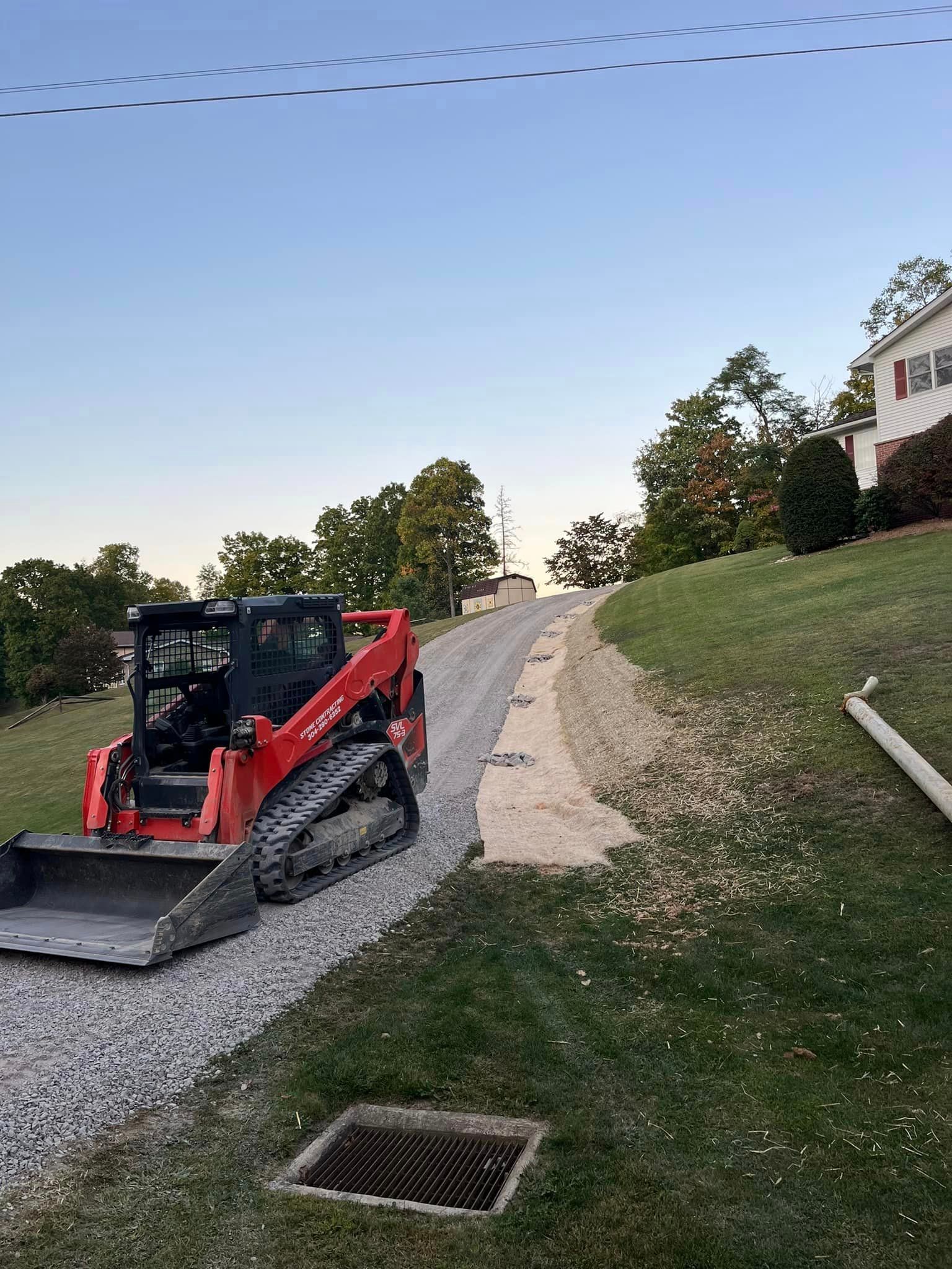 A red bulldozer is parked on the side of a gravel road.