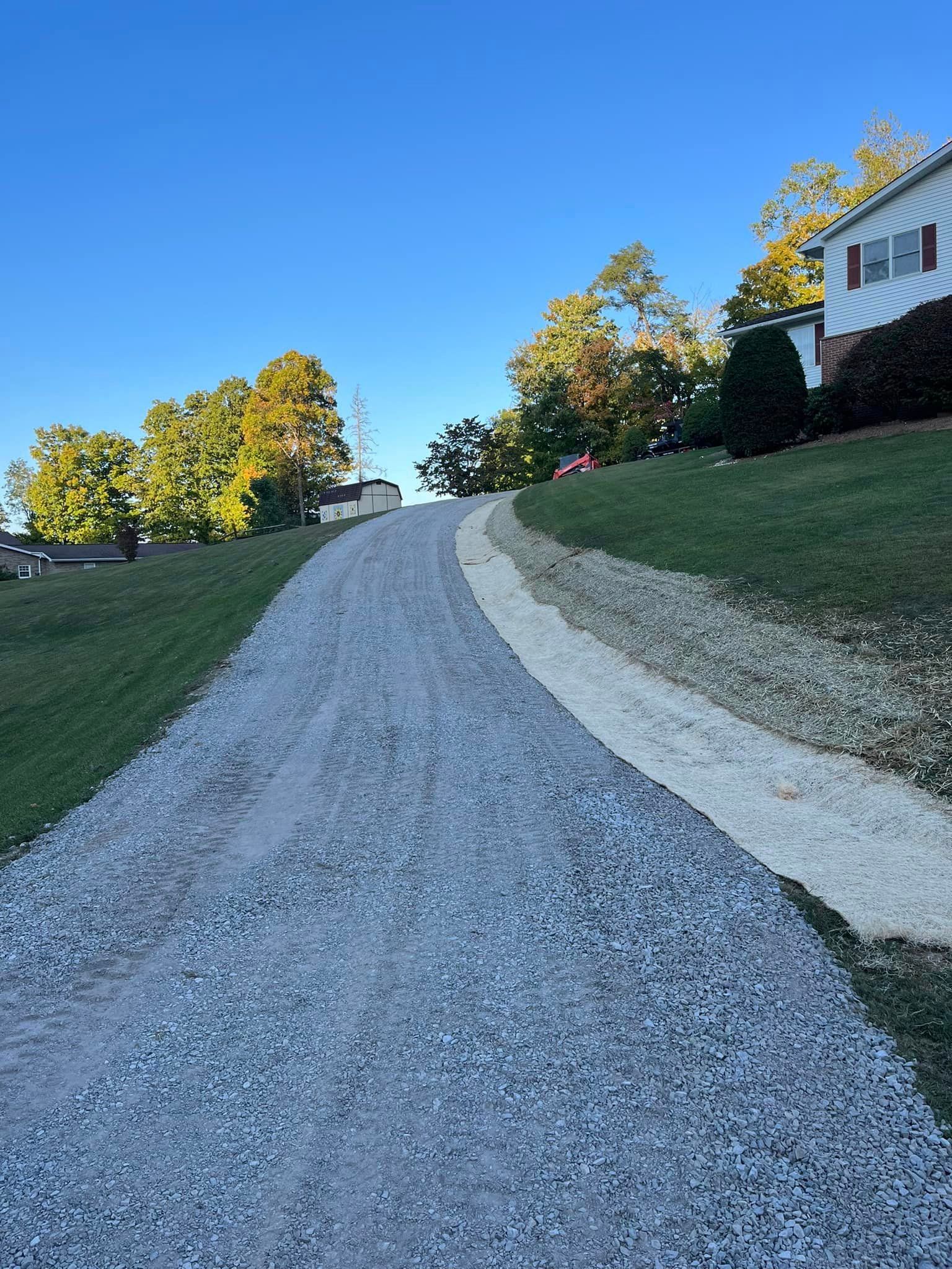 A gravel driveway leading to a house on a sunny day.