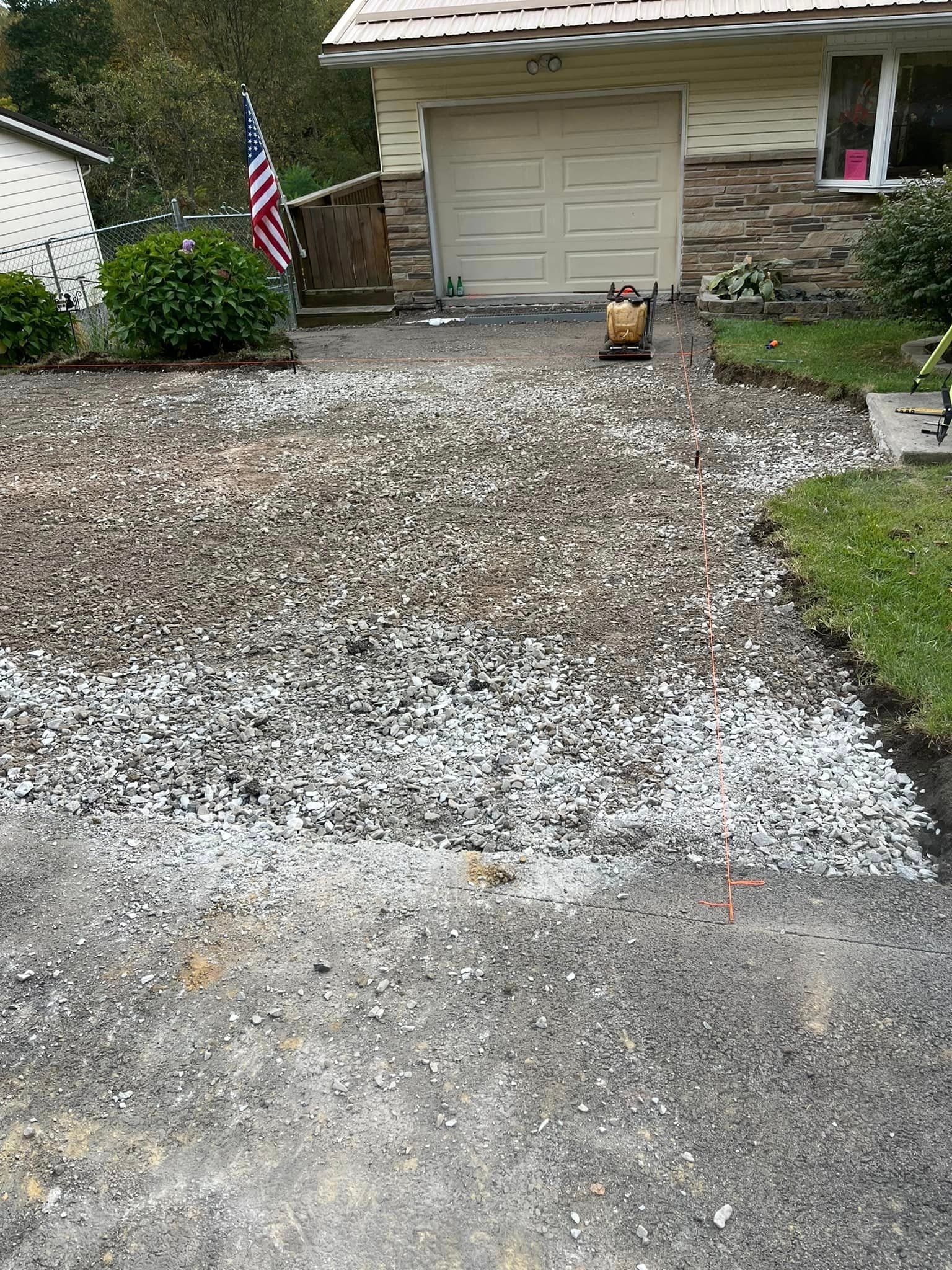 A gravel driveway in front of a house with an american flag.