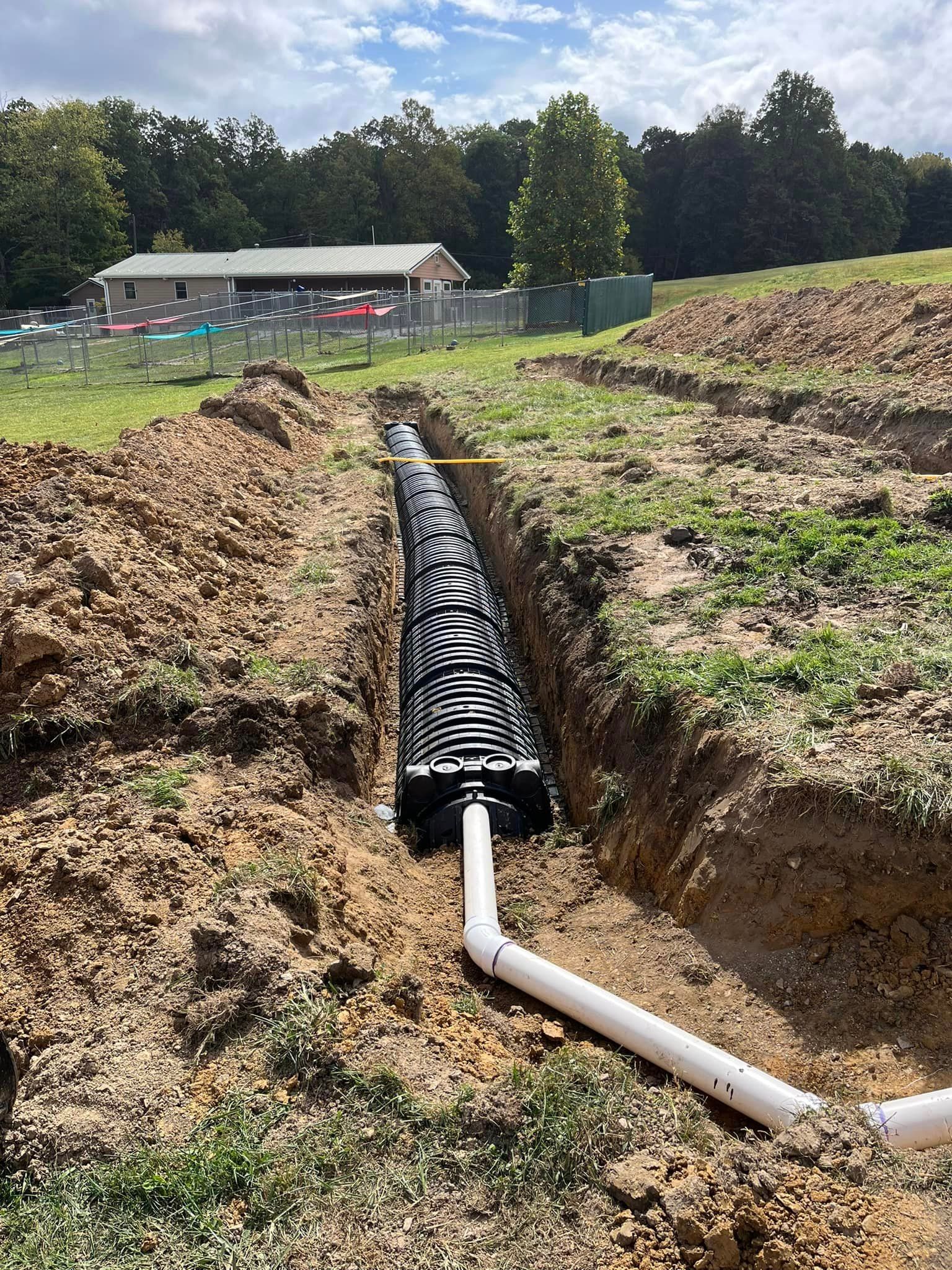 A large pipe is being installed in the dirt in a field.