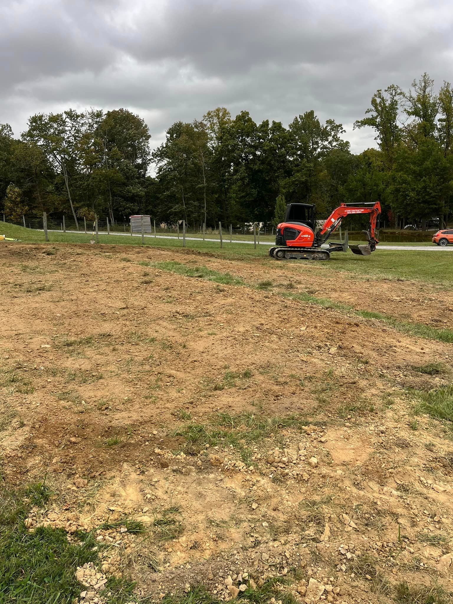 A red excavator is sitting in the middle of a field.