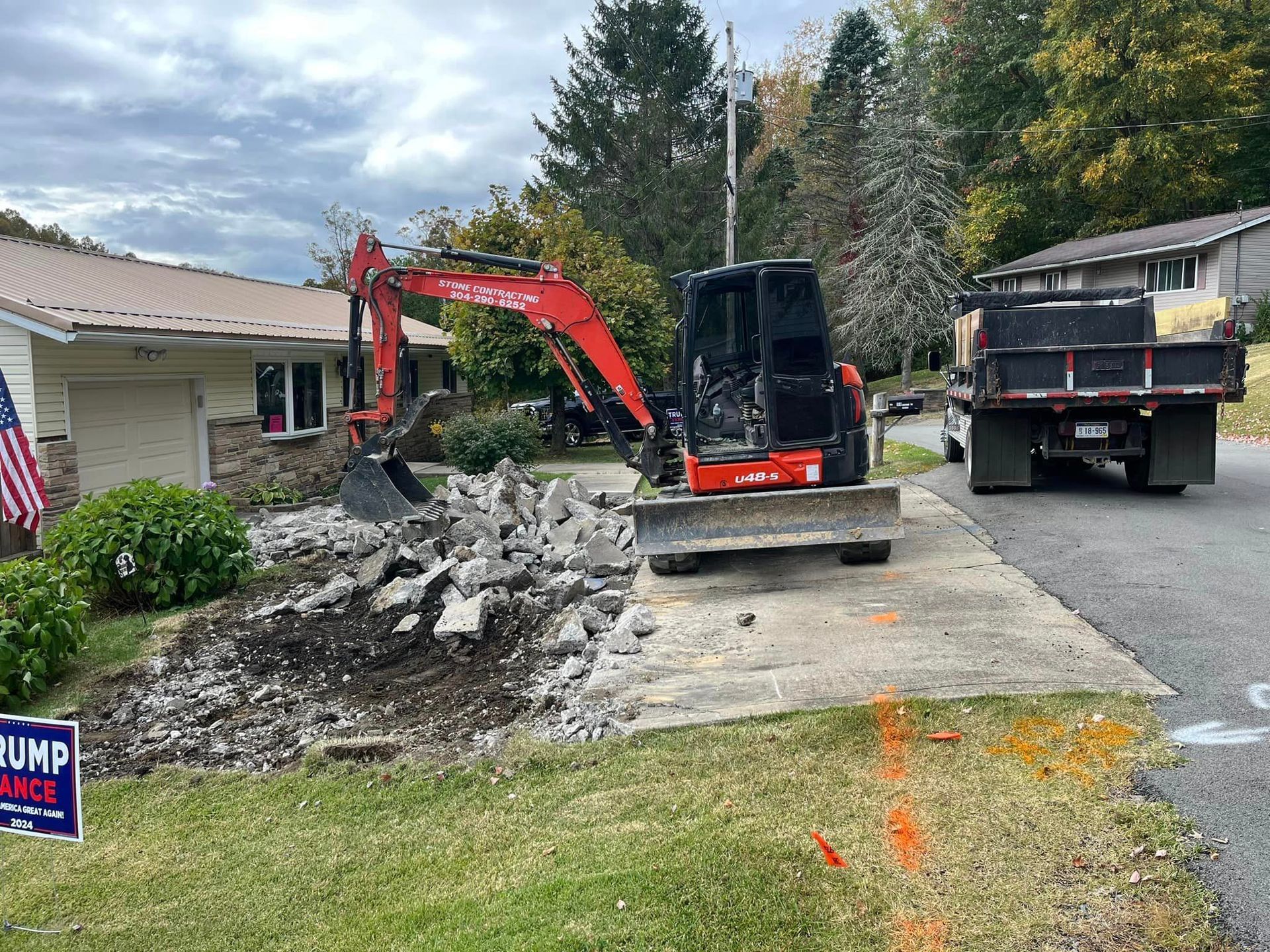 An excavator is digging a hole in front of a house.