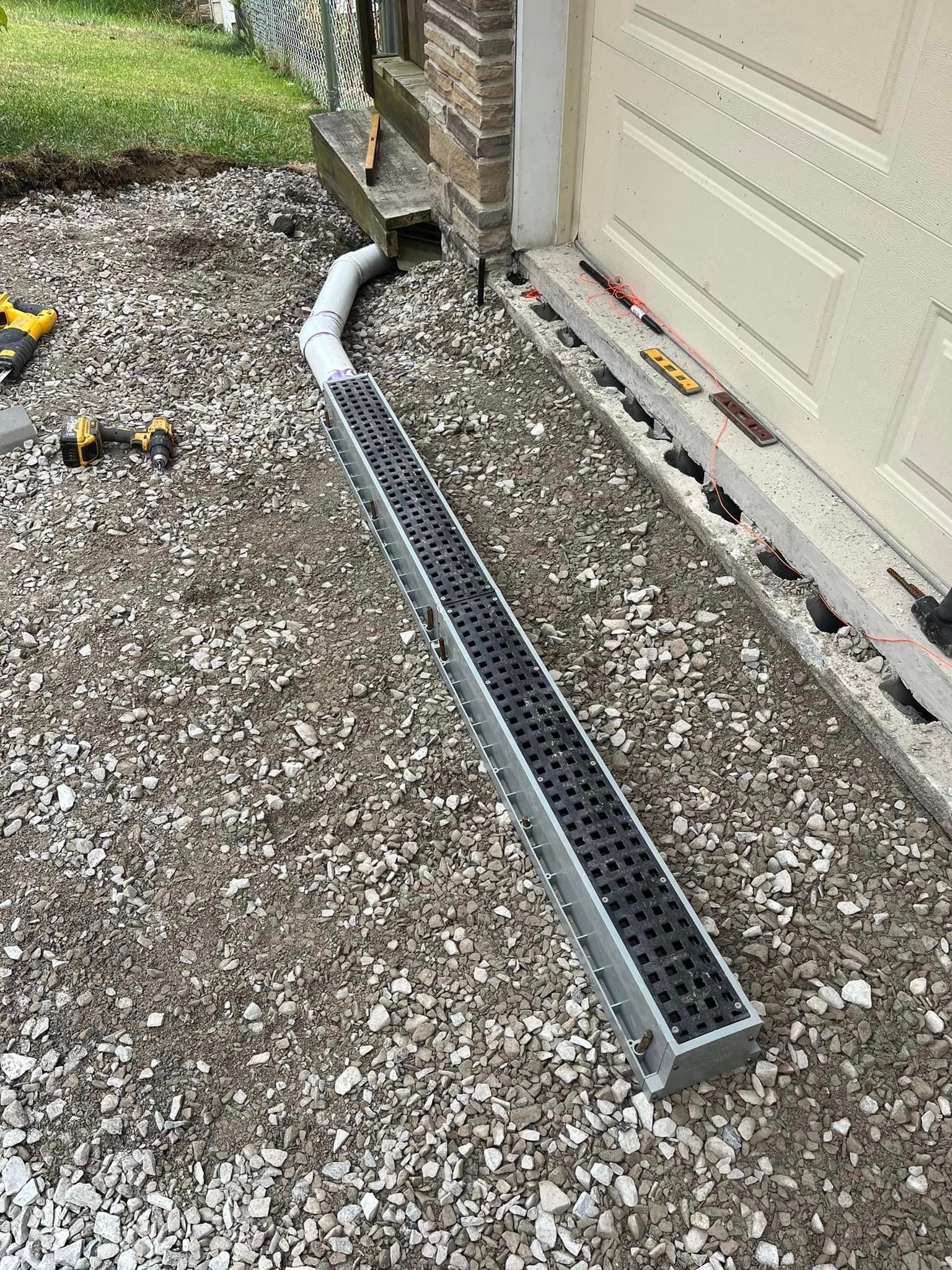 A drain is sitting on the ground next to a garage door.