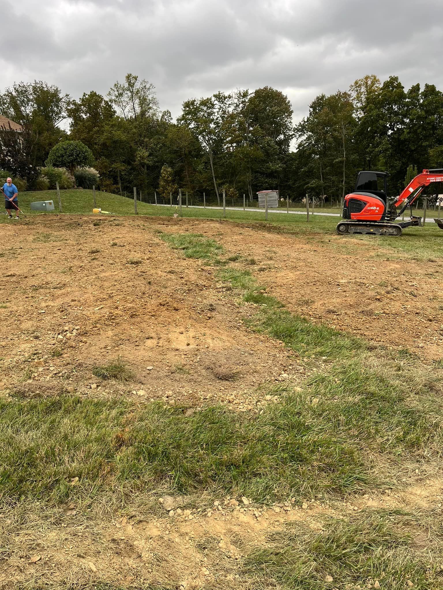 An excavator is sitting in the middle of a grassy field.