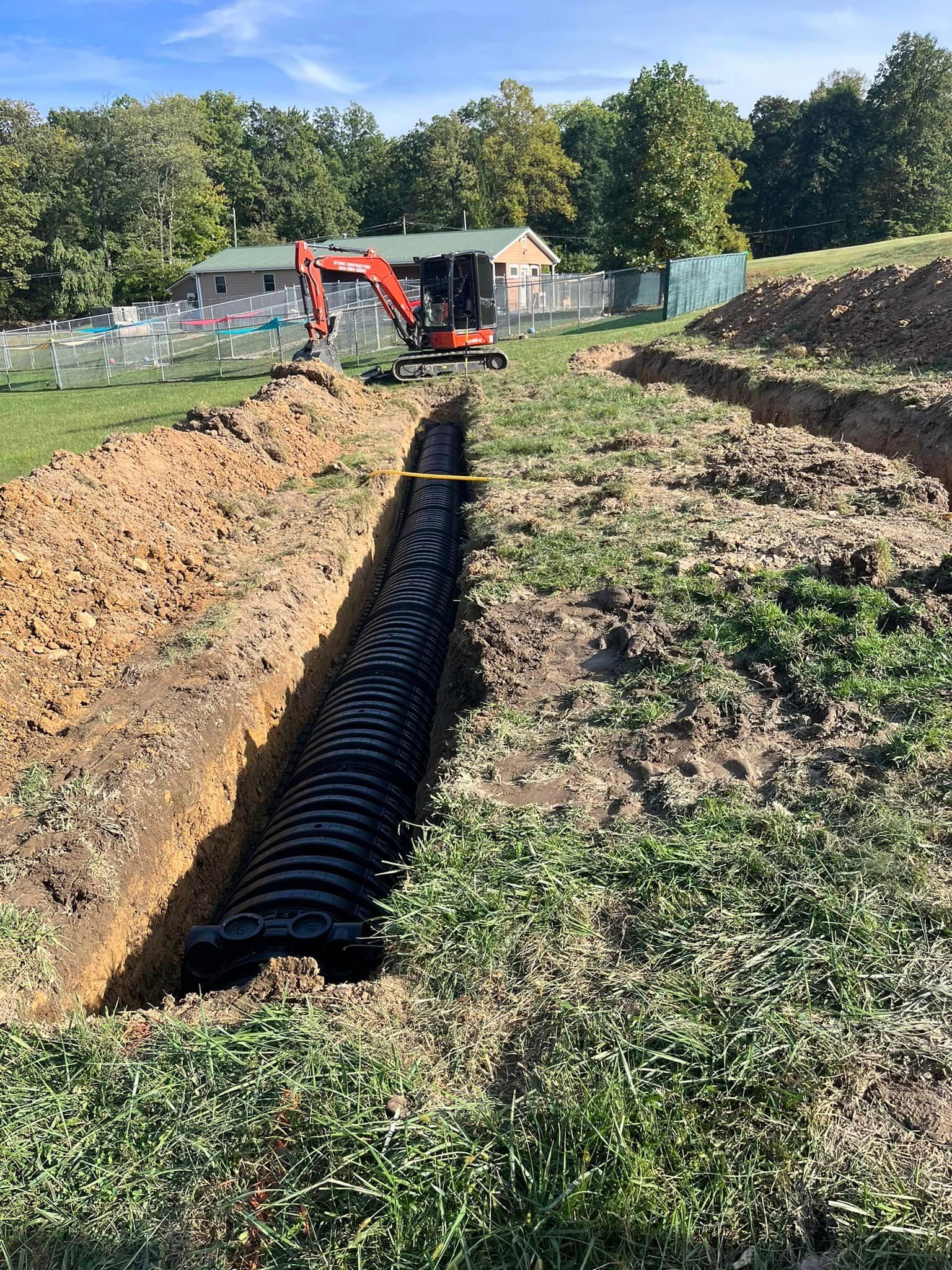 A large pipe is being installed in the ground in a field.