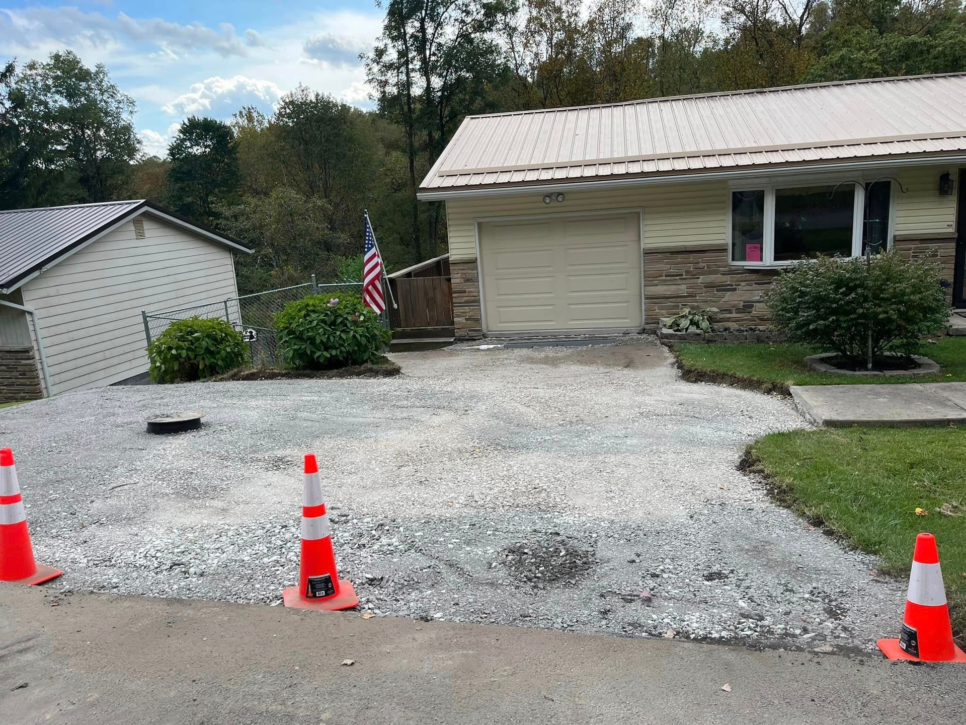 A driveway with orange and white traffic cones in front of a house.