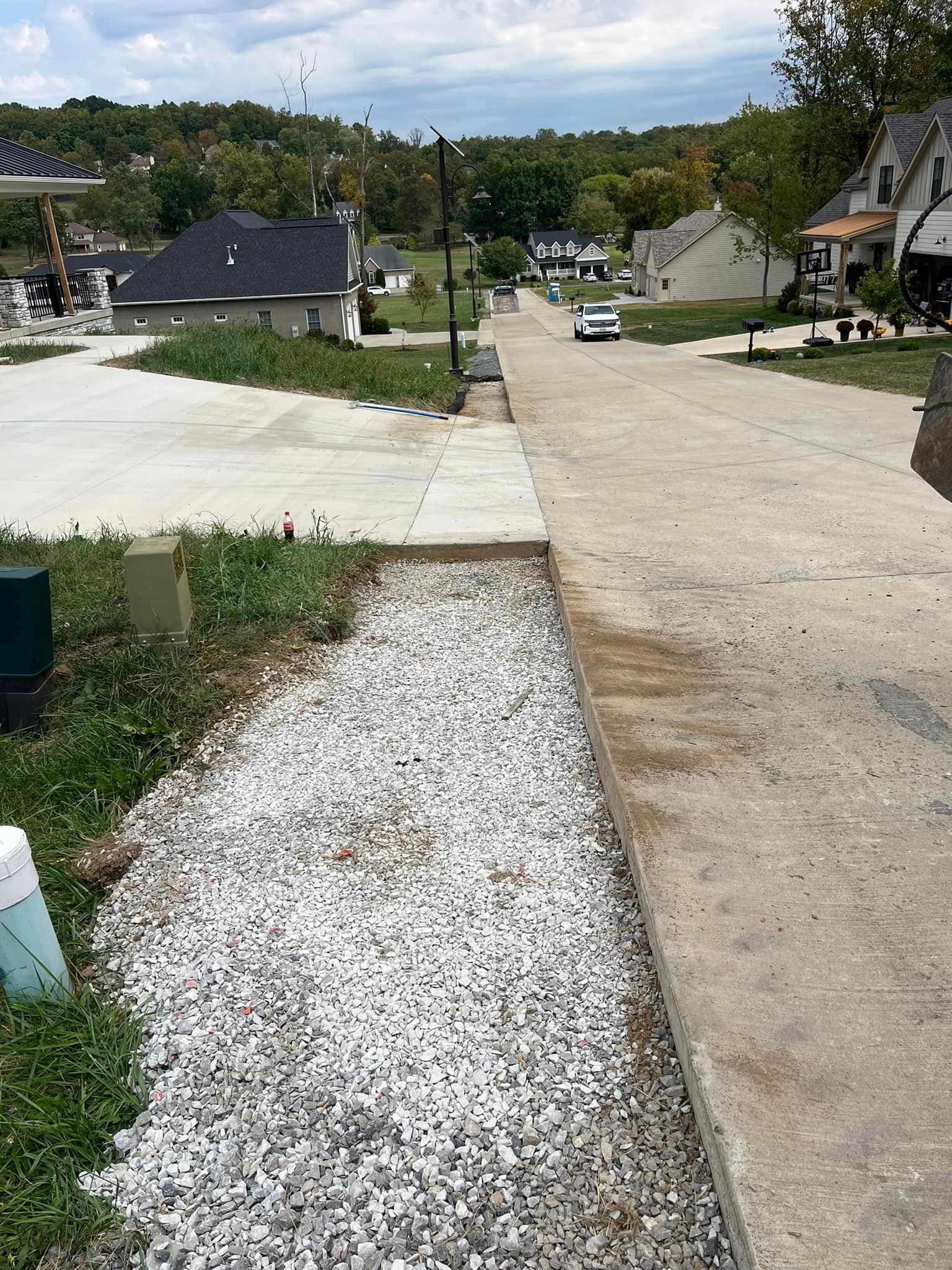 A gravel path leading to a street with houses in the background.