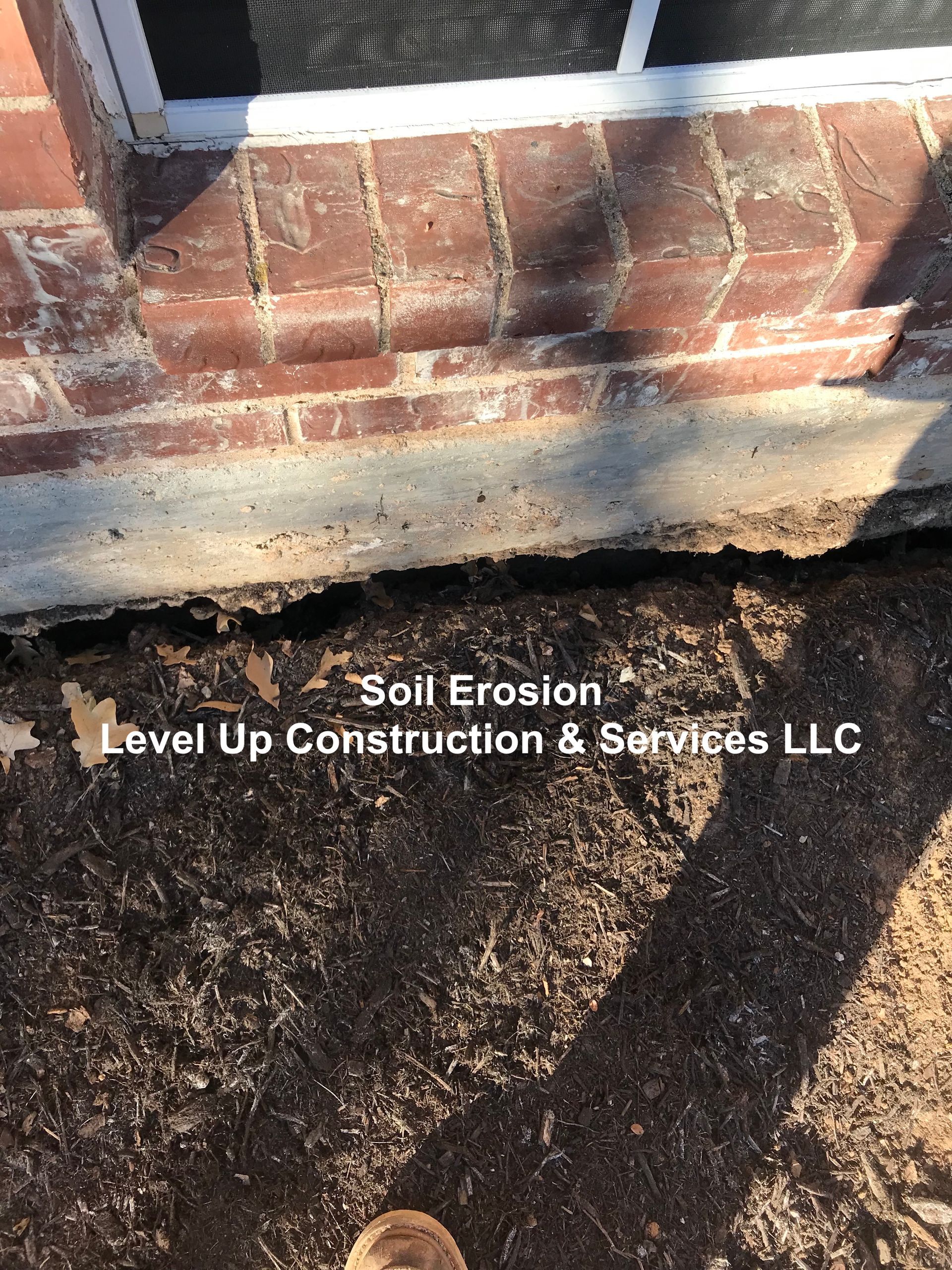 A person is standing in front of a brick building with a hole in the ground.