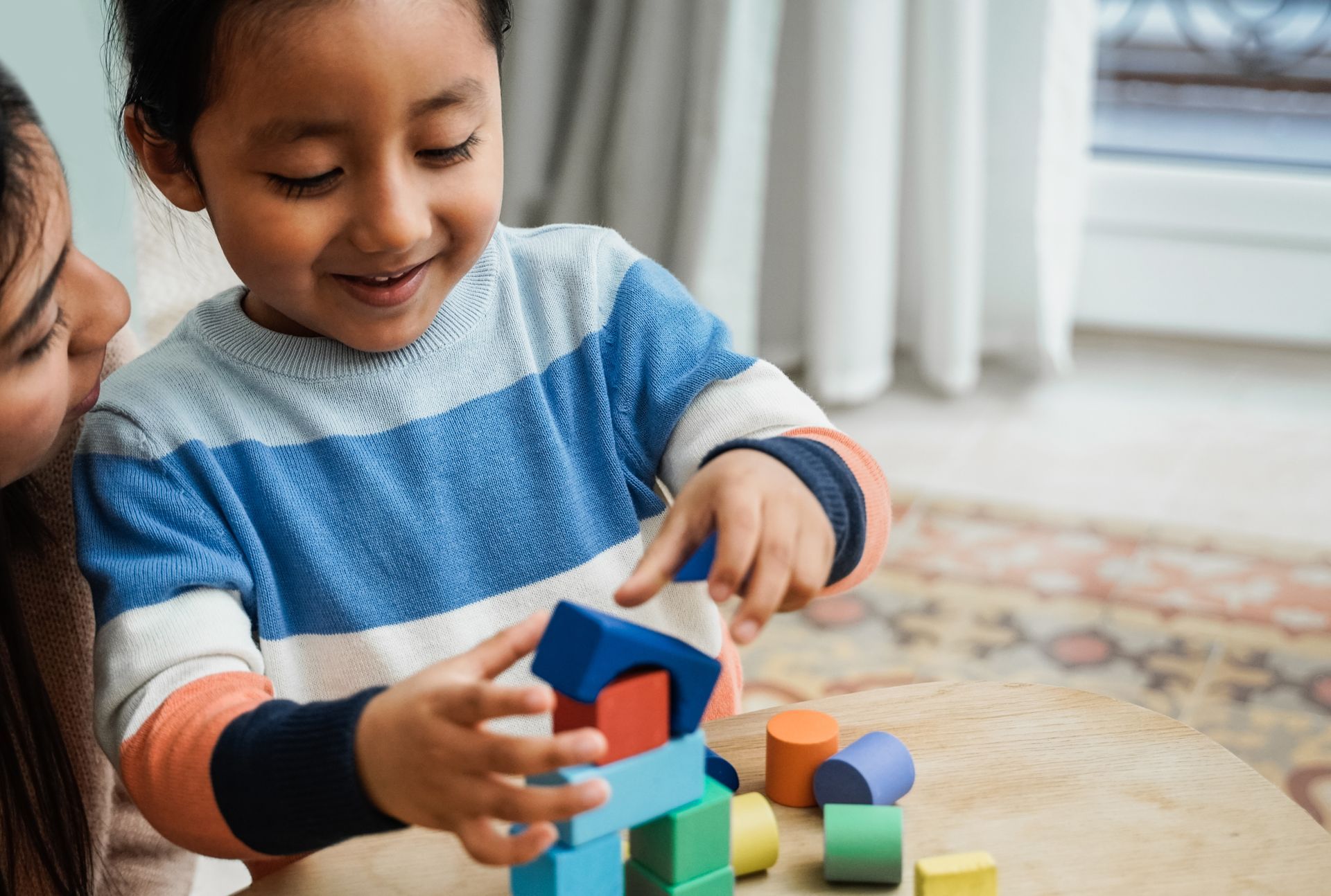 A little girl is playing with wooden blocks with her mother.