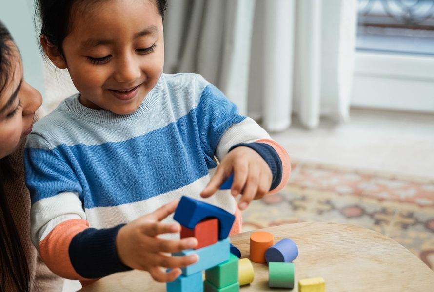 A little girl is playing with wooden blocks with her mother.