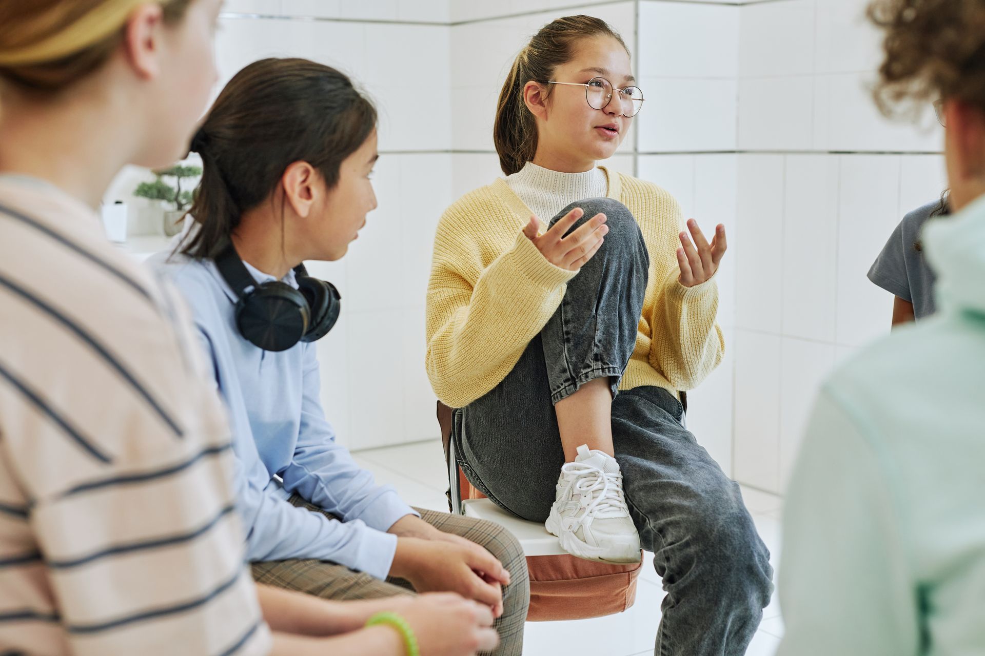 A group of young people are sitting in a circle talking to each other.