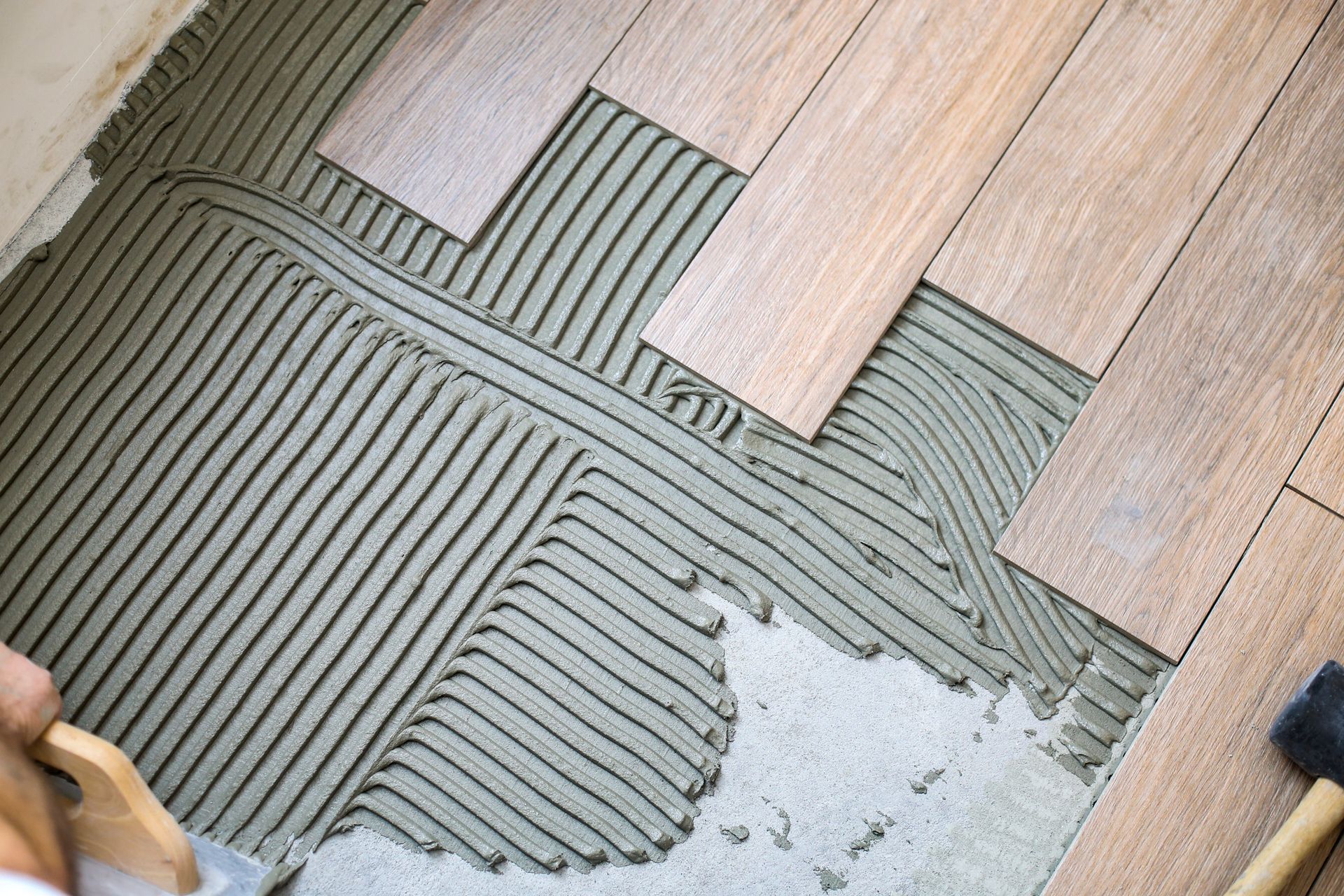 Installation of wooden floorboards with adhesive spread on the subfloor.