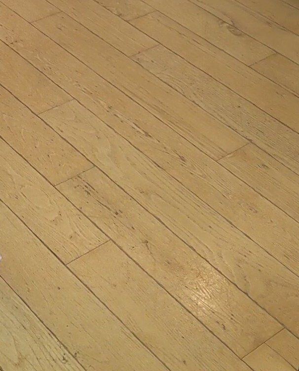 Light wooden floorboards laid at an angle, showing visible grain and wear.