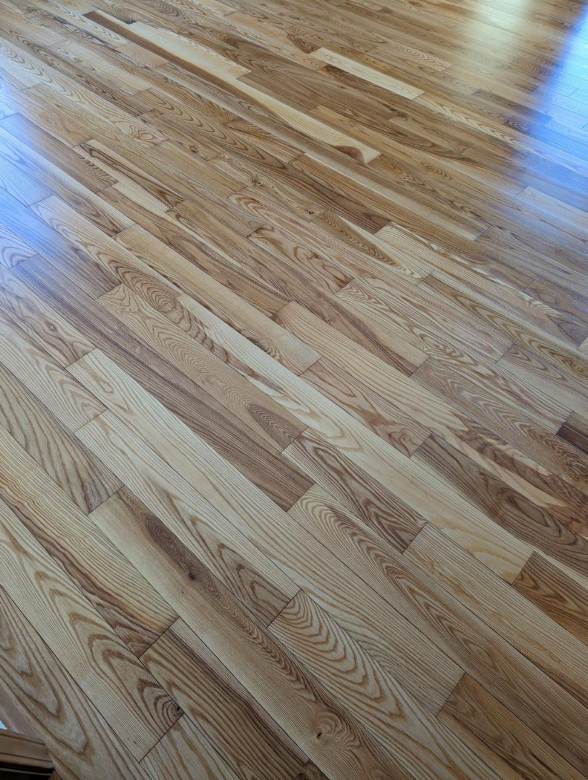 Wooden hardwood floor with light brown planks in a diagonal pattern.