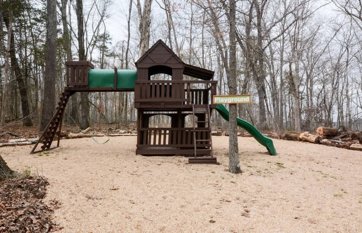 A wooden playground with a slide and stairs in the middle of the woods.