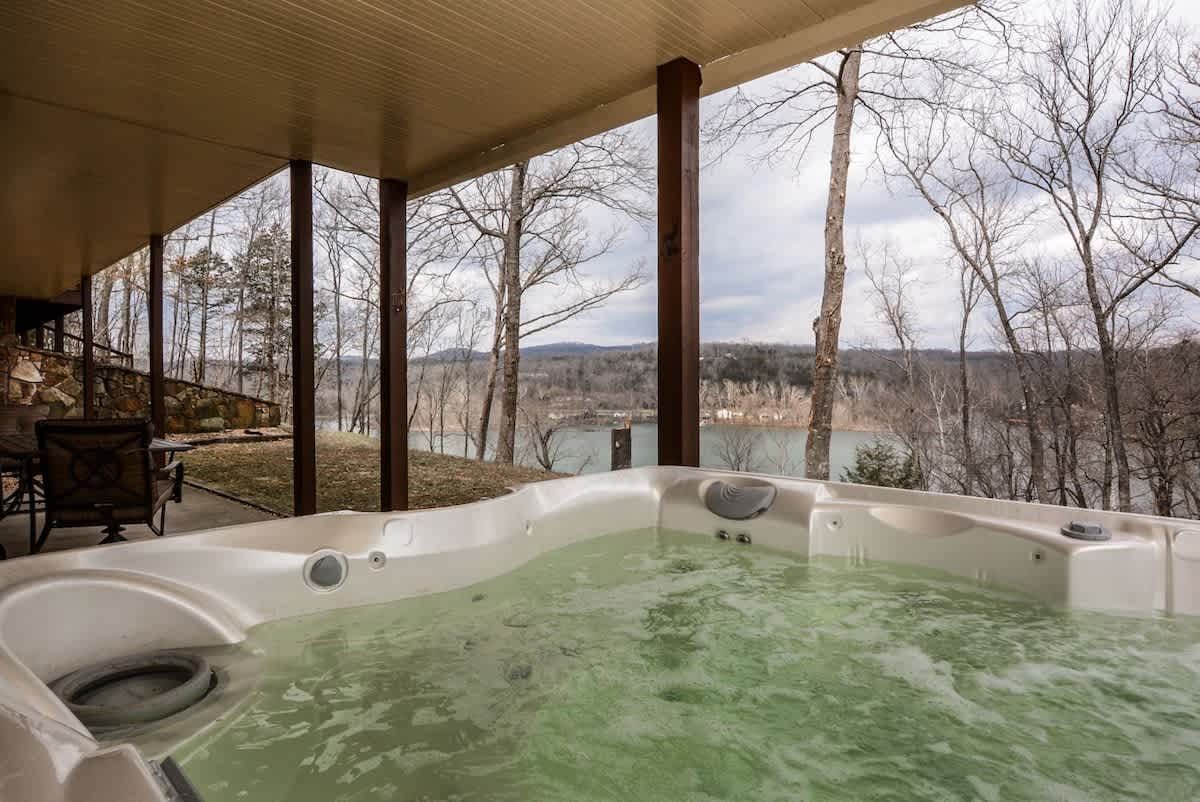 A hot tub is sitting on a porch overlooking a lake.