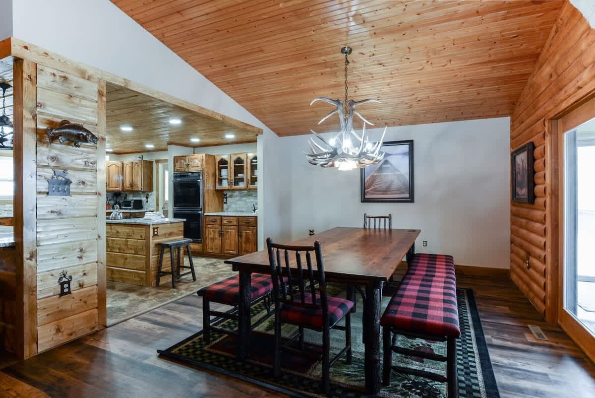 A dining room with a table and chairs in a log cabin.