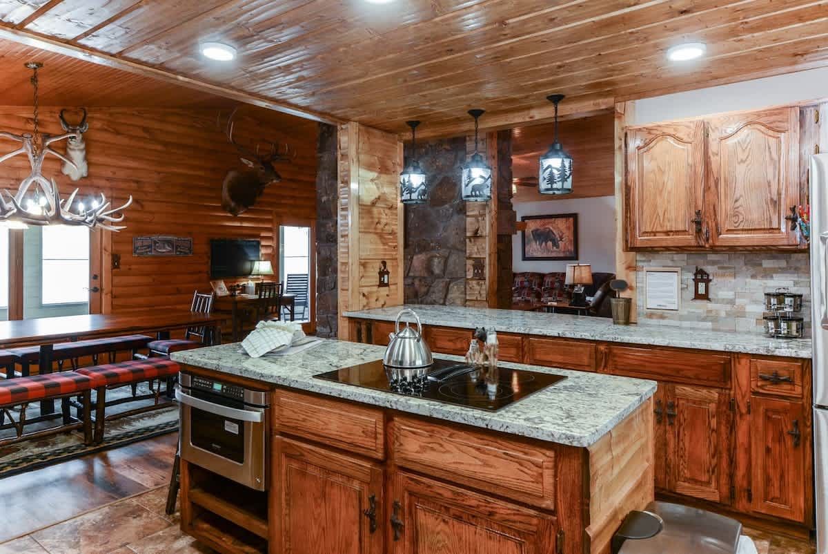 A kitchen in a log cabin with wooden cabinets and granite counter tops.