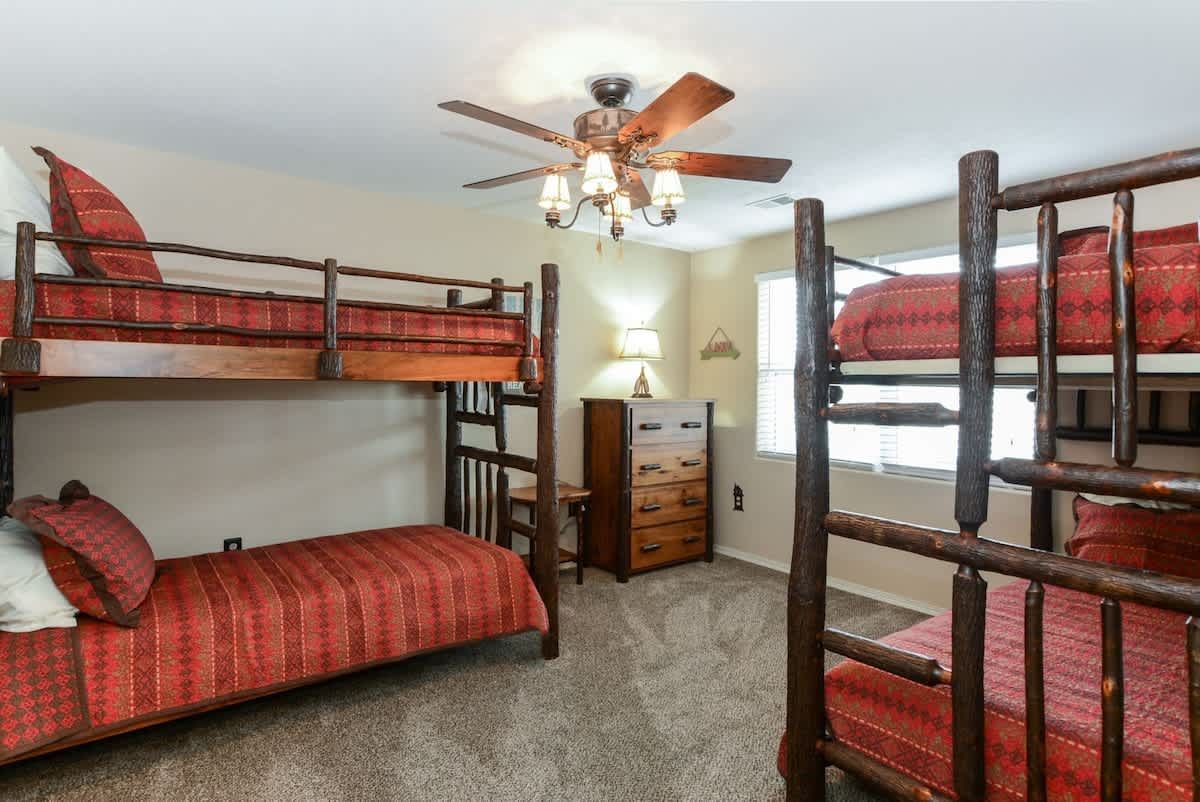A bedroom with three bunk beds and a ceiling fan