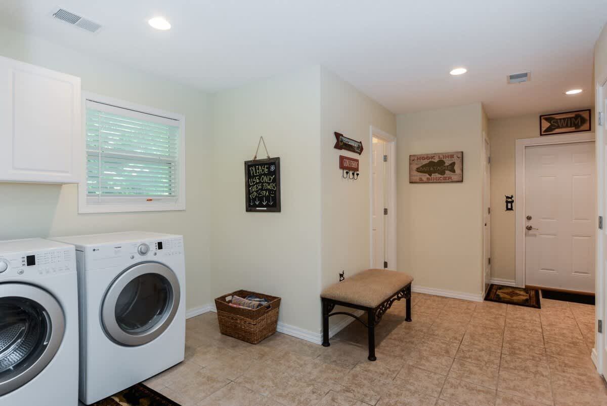 A laundry room with a washer and dryer and a bench.