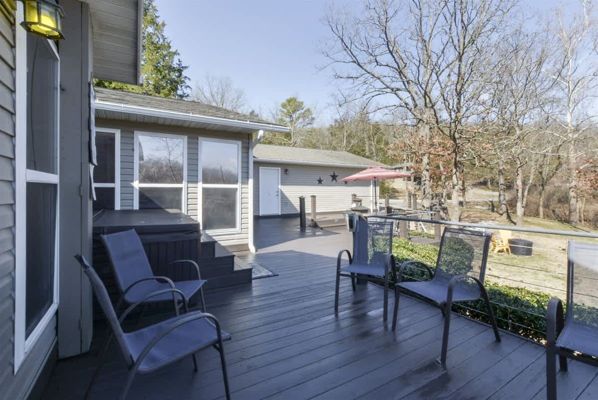 A deck with chairs and umbrellas in front of a house.
