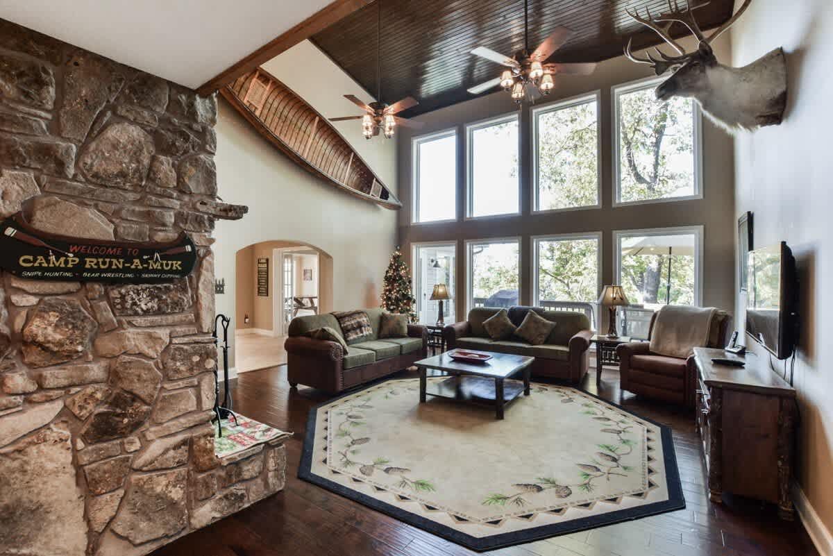 A living room with a couch , chairs , a fireplace and a deer head on the wall.