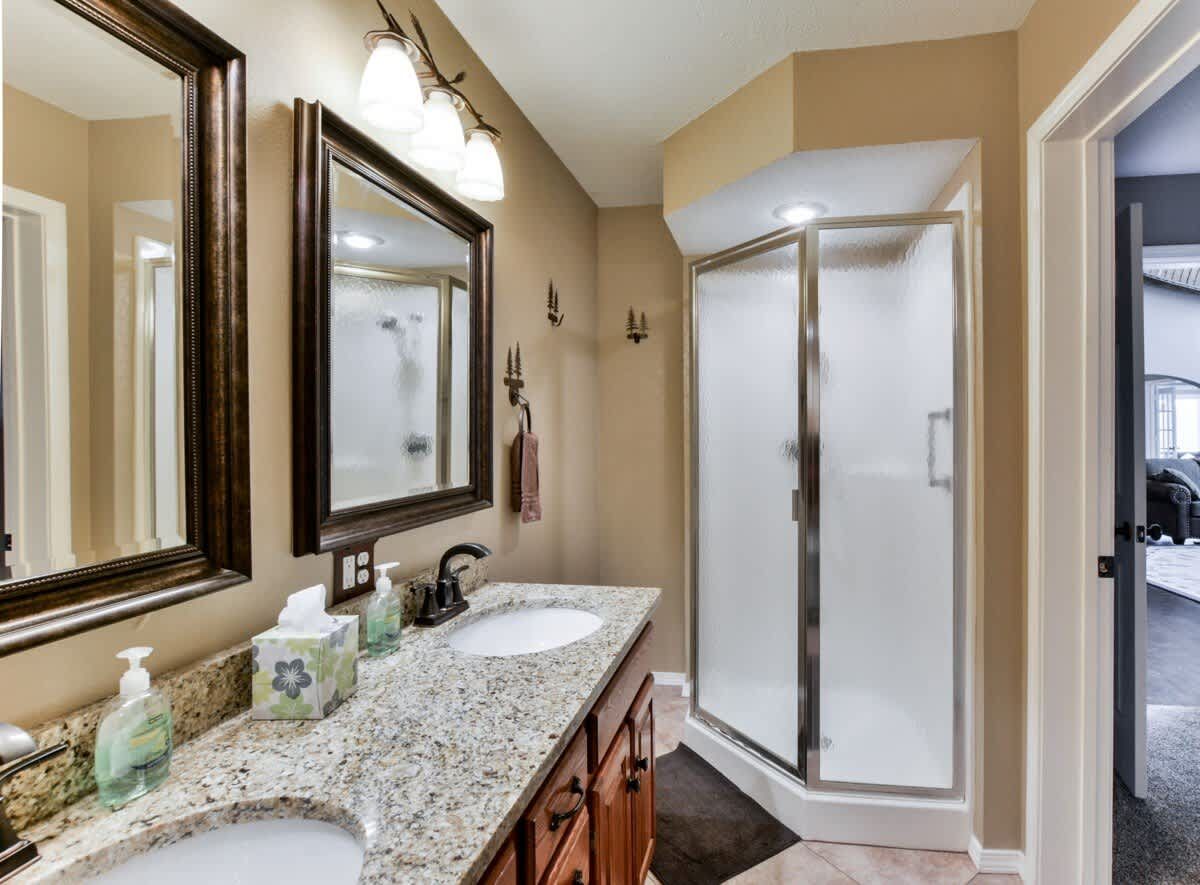 A bathroom with two sinks and a walk in shower.