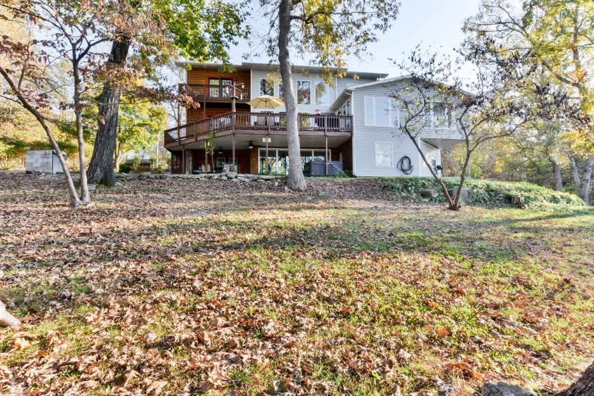 A large house is sitting on top of a hill surrounded by trees and leaves.