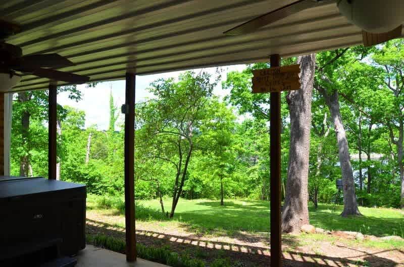 A porch with a hot tub and trees in the background.