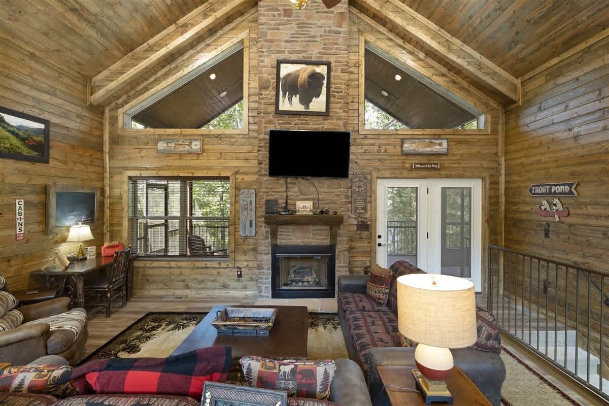 A living room in a log cabin with a fireplace and a flat screen tv.