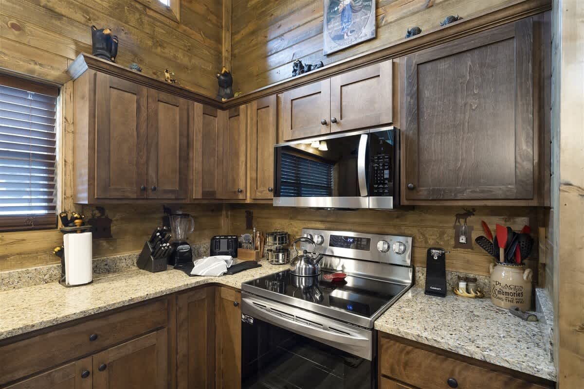 A kitchen in a log cabin with stainless steel appliances and granite counter tops.