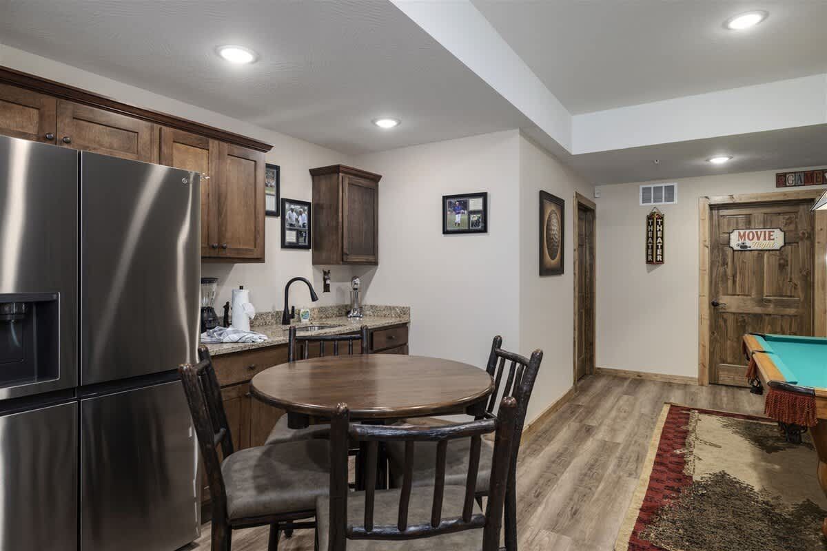 A kitchen with a table and chairs and a pool table.