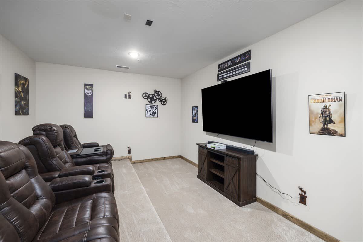 A home theater with a couch , chairs and a flat screen tv.