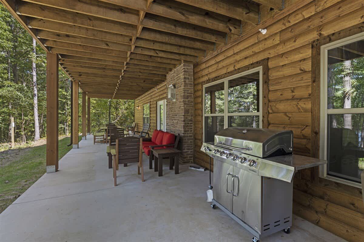 There is a grill on the porch of a log cabin.
